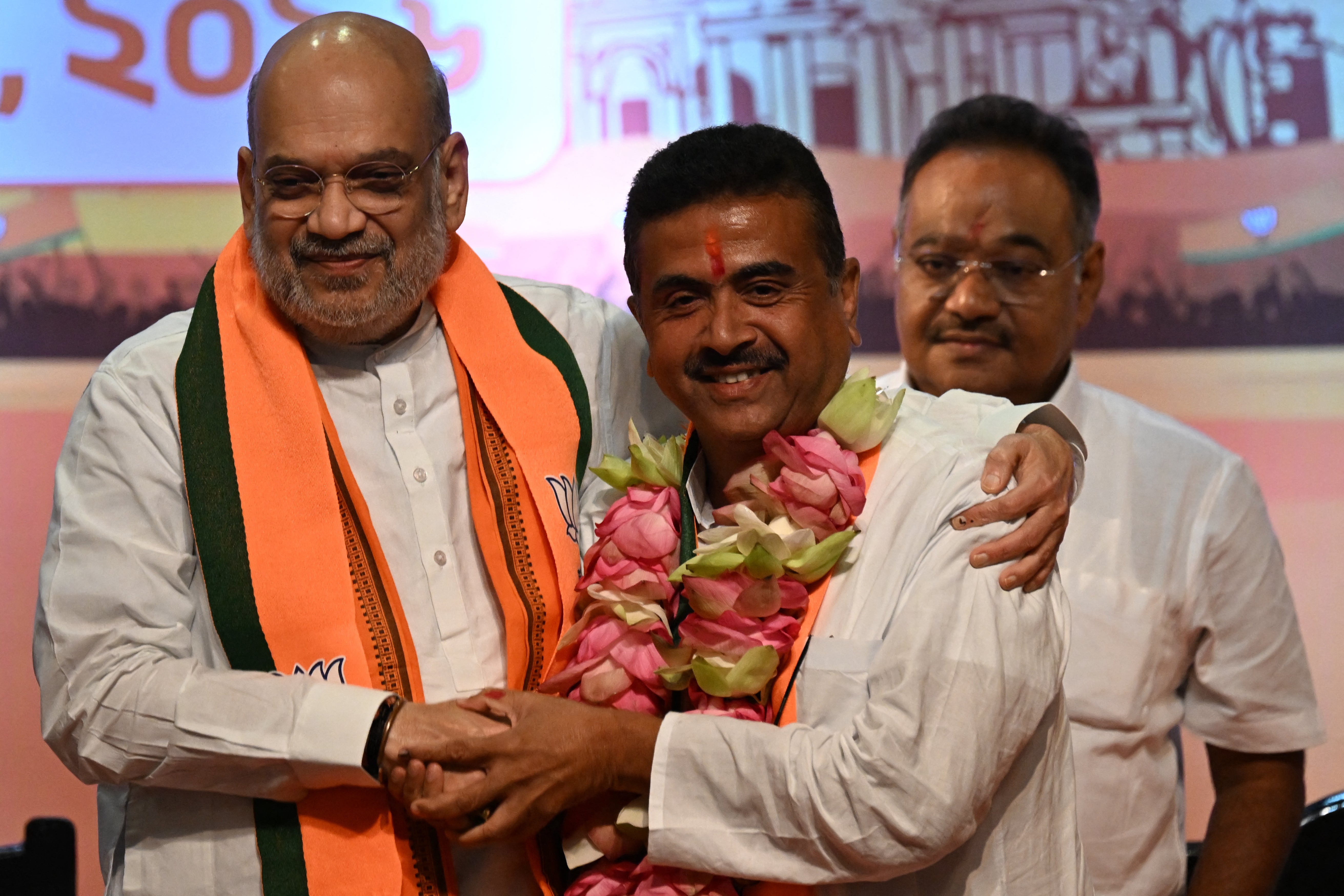 India's home minister Amit Shah (L) greets Bharatiya Janata Party (BJP) leader and newly selected chief minister of West Bengal Suvendu Adhikari (C) during a party meeting in Kolkata on 8 May 2026
