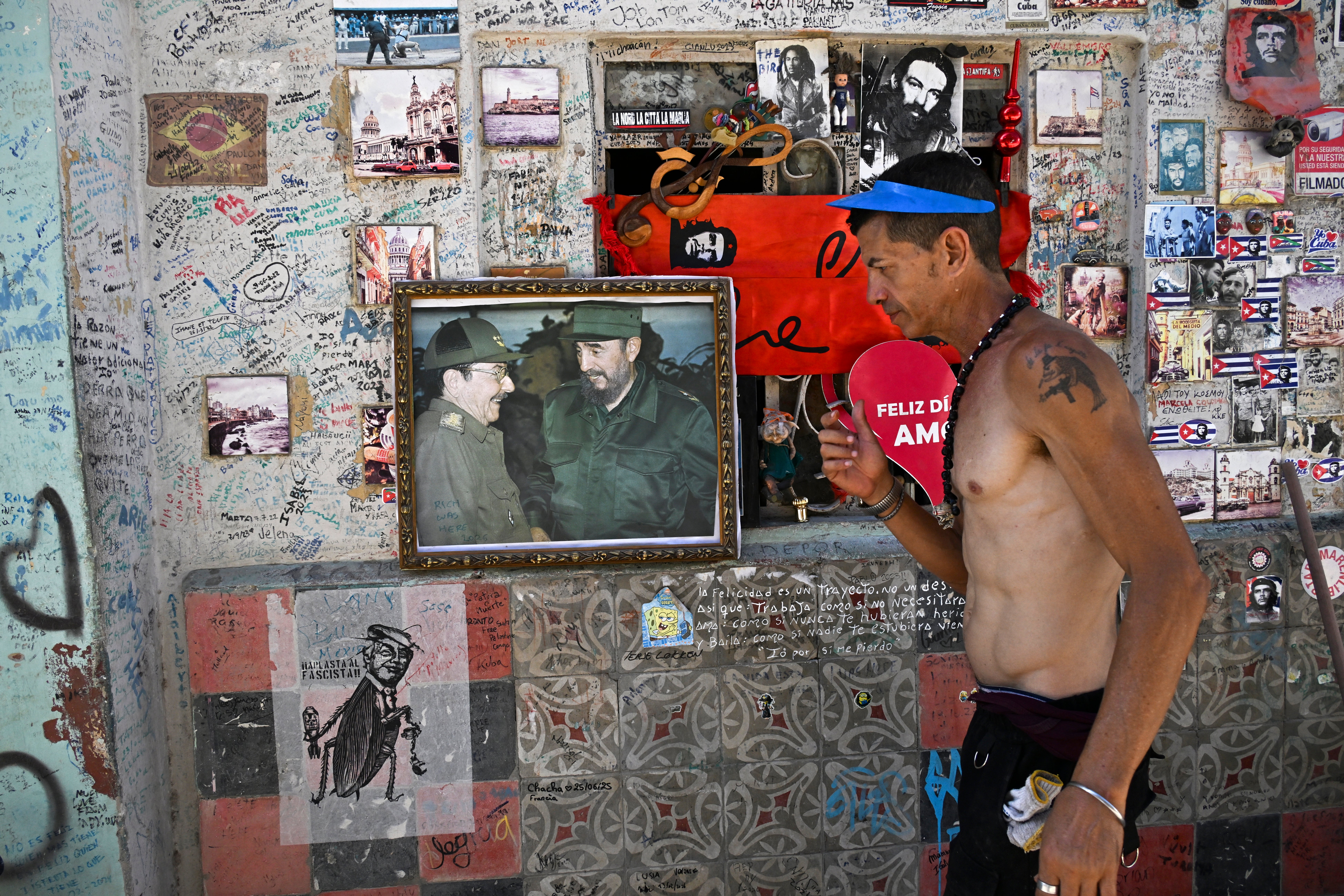 A man is seen next to a photo of former Cuba's President Raul Castro and late Cuba's leader Fidel Castro at his home in Havana