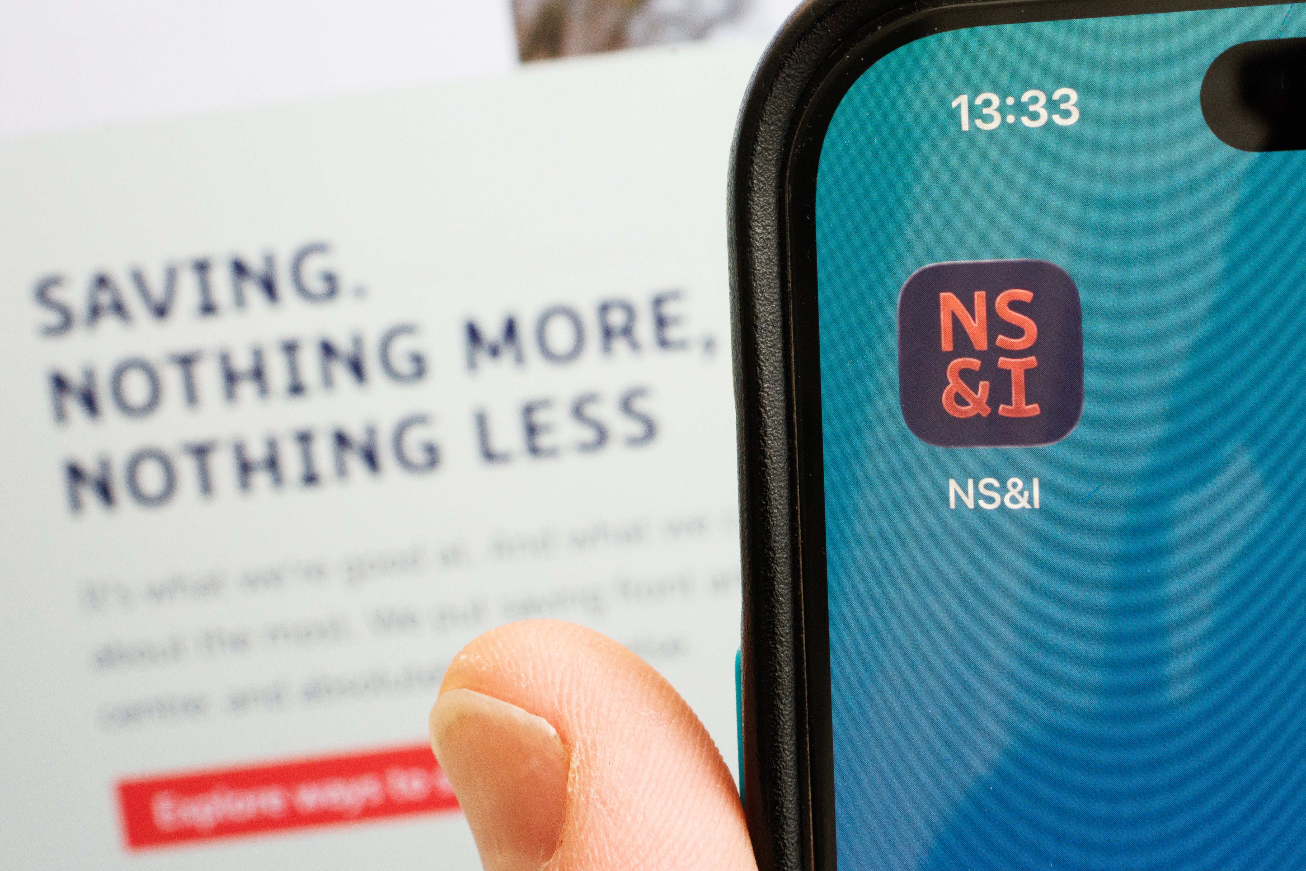 The logo of the National Savings and Investments bank is displayed on a mobile phone