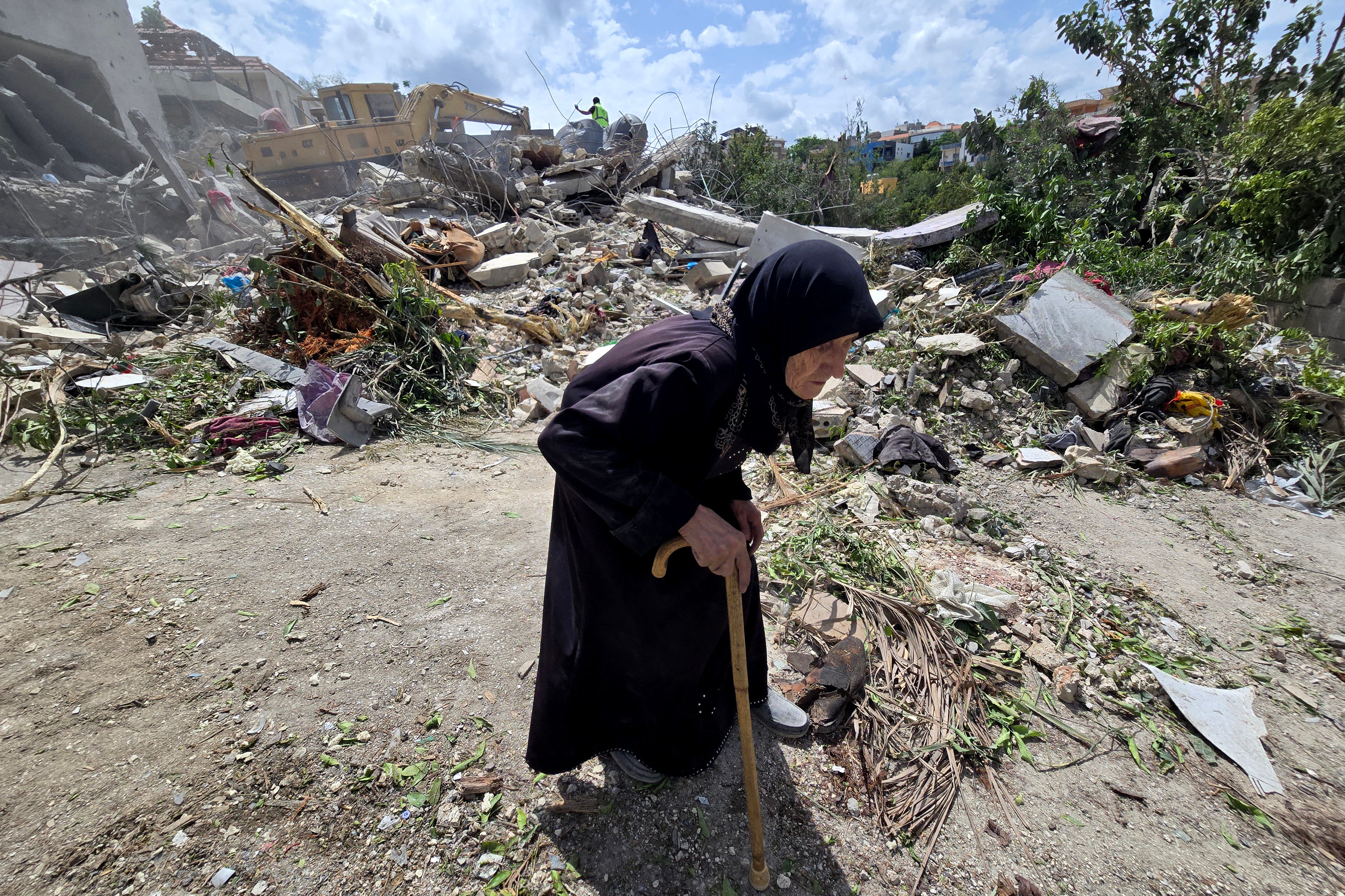 An elderly woman walks past Lebanese civil defence workers searching through the rubble in the southern Lebanese village of Deir Qanun al-Nahr on May 20, 2026, a day after Israeli strikes. Israeli strikes on south Lebanon killed 19 people, the health ministry said, as Hezbollah reported clashes with Israeli troops despite a truce in the war. (AFP/Getty)