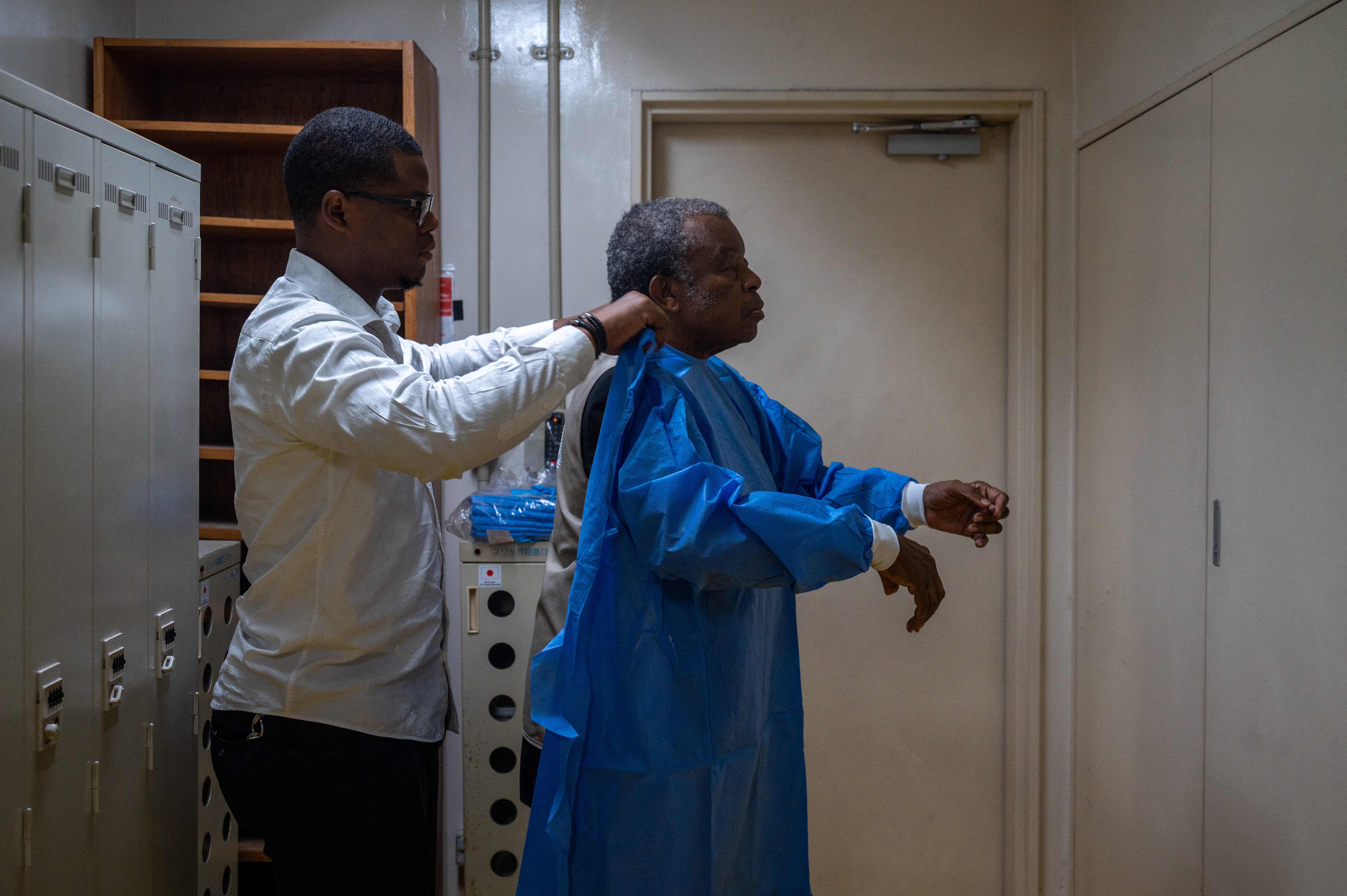 A worker, left, helps Professor Jean-Jacques Muyembe, director general of the National Institute for Biomedical Research to put on protective equipment before entering a laboratory in Kinshasa, the capital of the Democratic Republic of the Congo