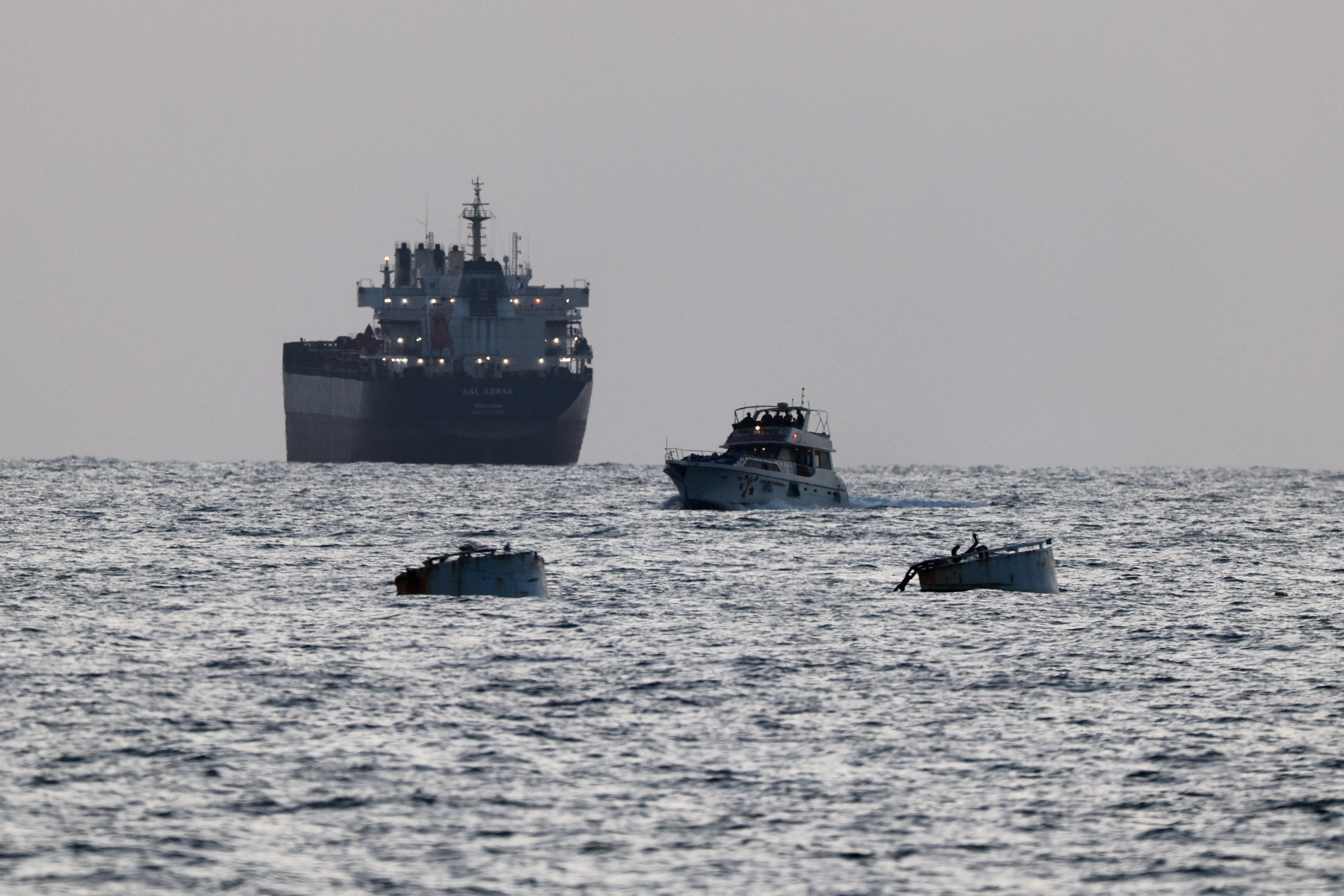 Israeli soldiers are seen on a vessel bearing symbols of the Global Sumud Flotilla, with a cargo ship behind it, as seen from Ashdod