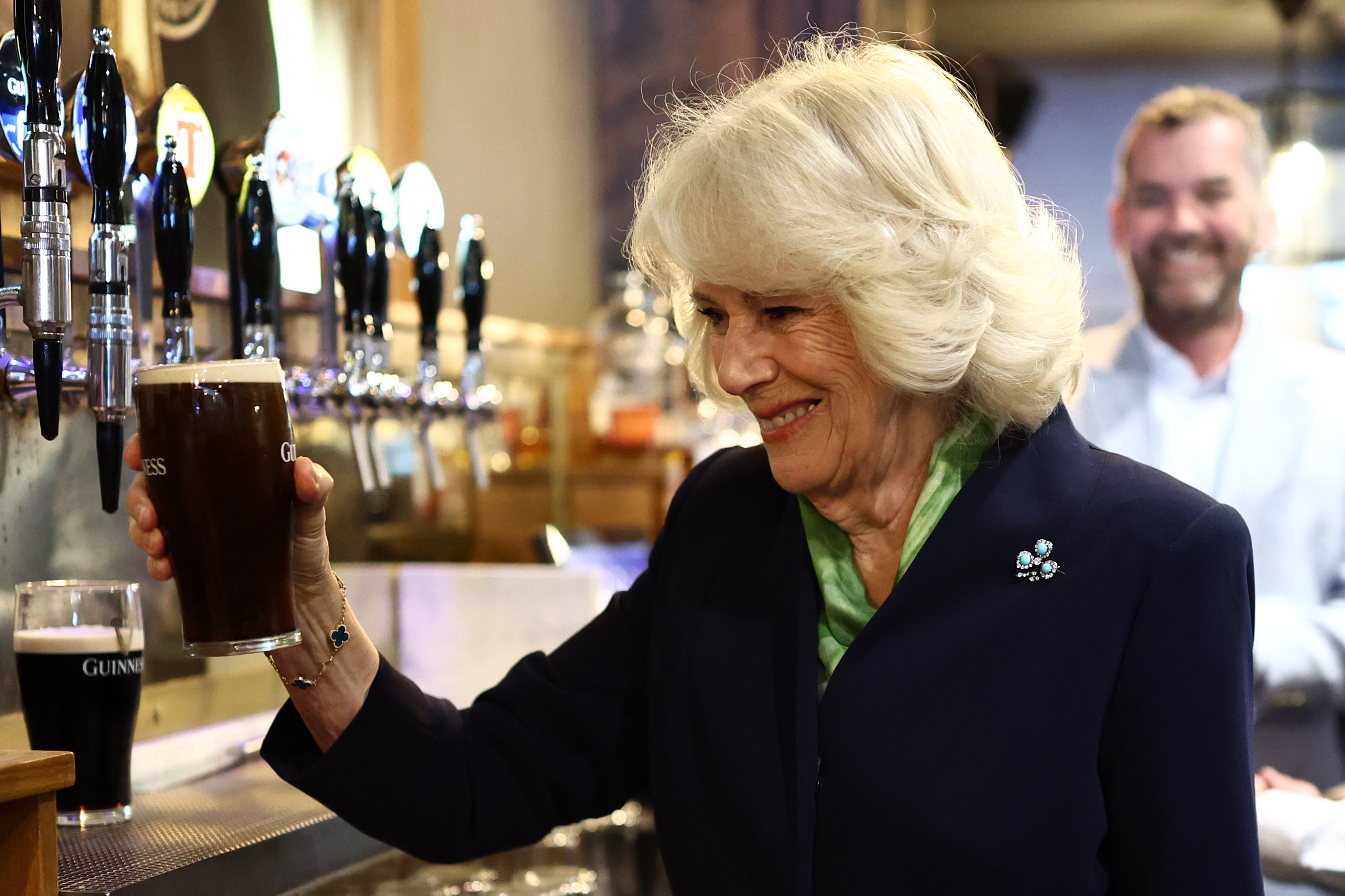 Queen Camilla admires a pint of Guinness that she poured during a visit to The Parson's Nose pub in Hillsborough