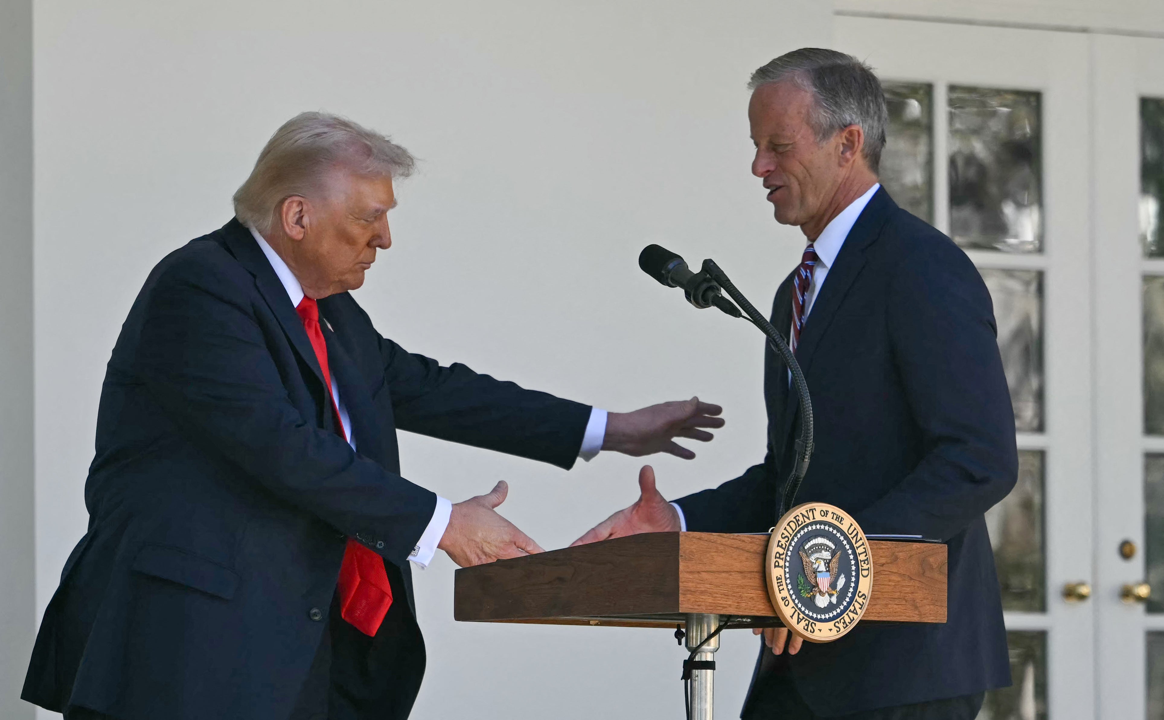 US President Donald Trump greets Senate Majority Leader John Thune, Republican of South Dakota, at the lectern during a "Rose Garden Club" lunch in October