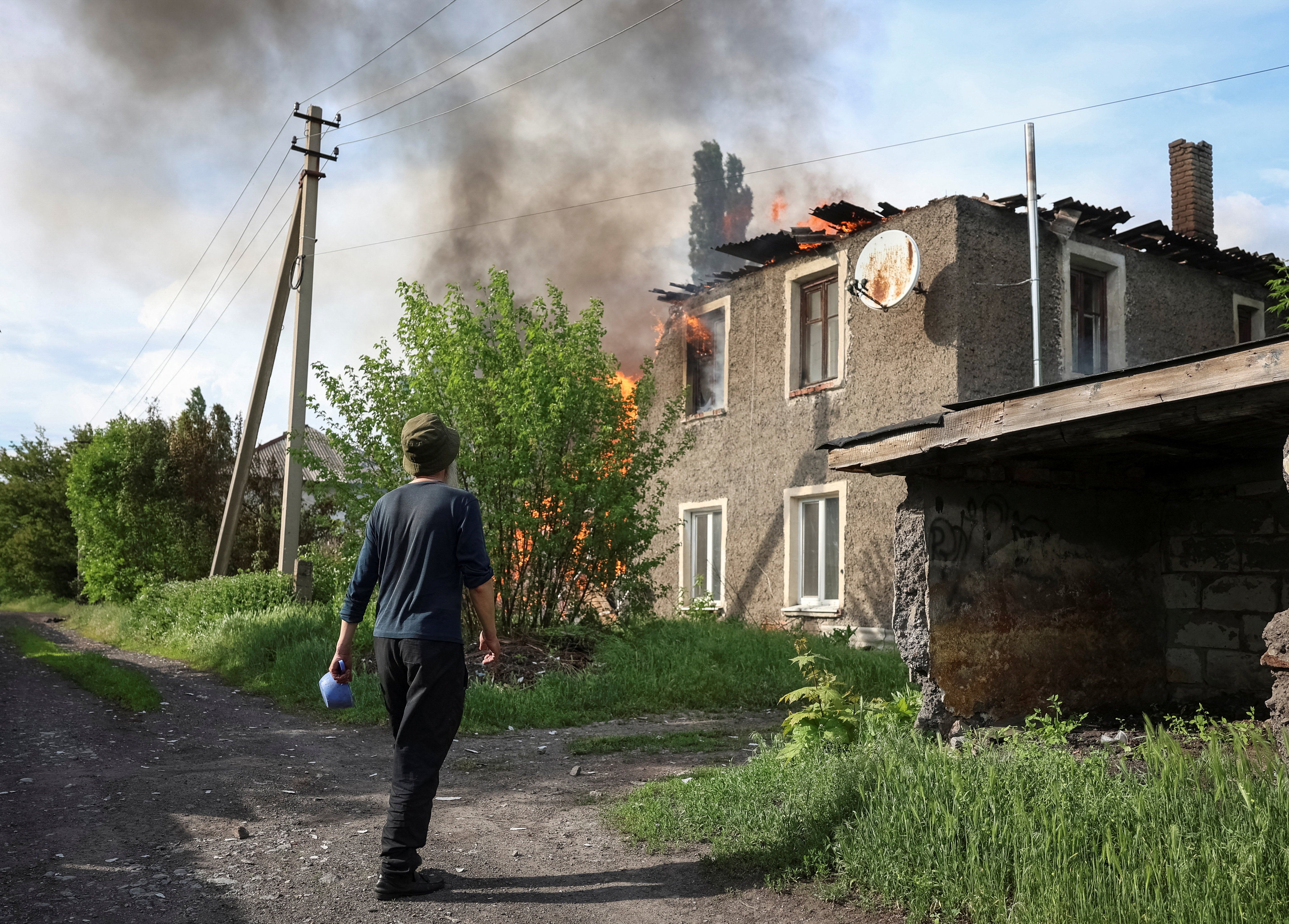 A resident stands near a burning house hit by Russian drone, amid Russia's attack on Ukraine, in the frontline city of Bilozerske in Donetsk region, Ukraine May 20, 2026. REUTERS/Anatolii Stepanov (Reuters)