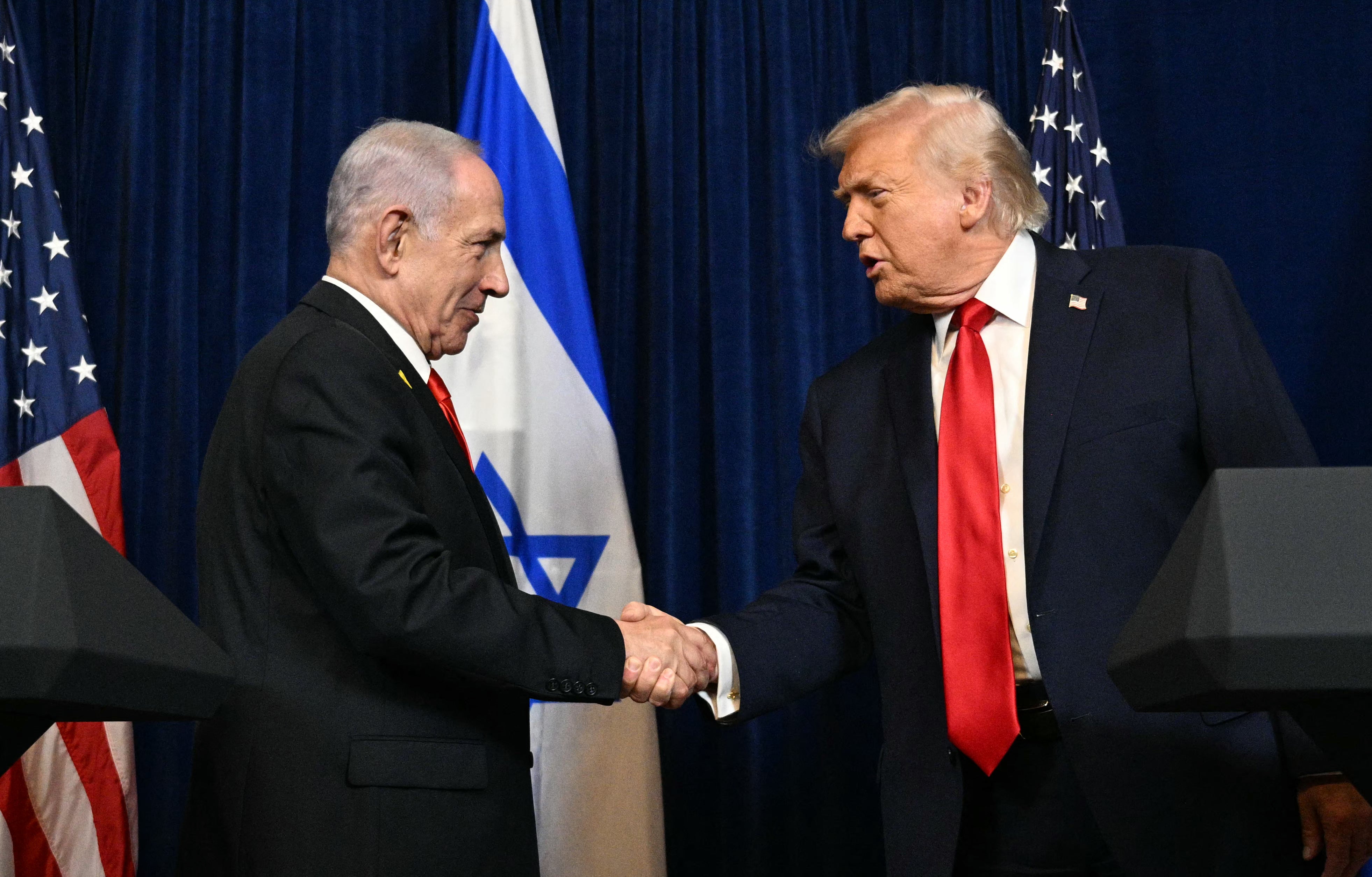Donald Trump (R) and Israeli Prime Minister Benjamin Netanyahu shake hands as they arrive to speak to journalists during a joint press conference at Trump's Mar-a-Lago residence in Palm Beach, Florida, on December 29, 2025