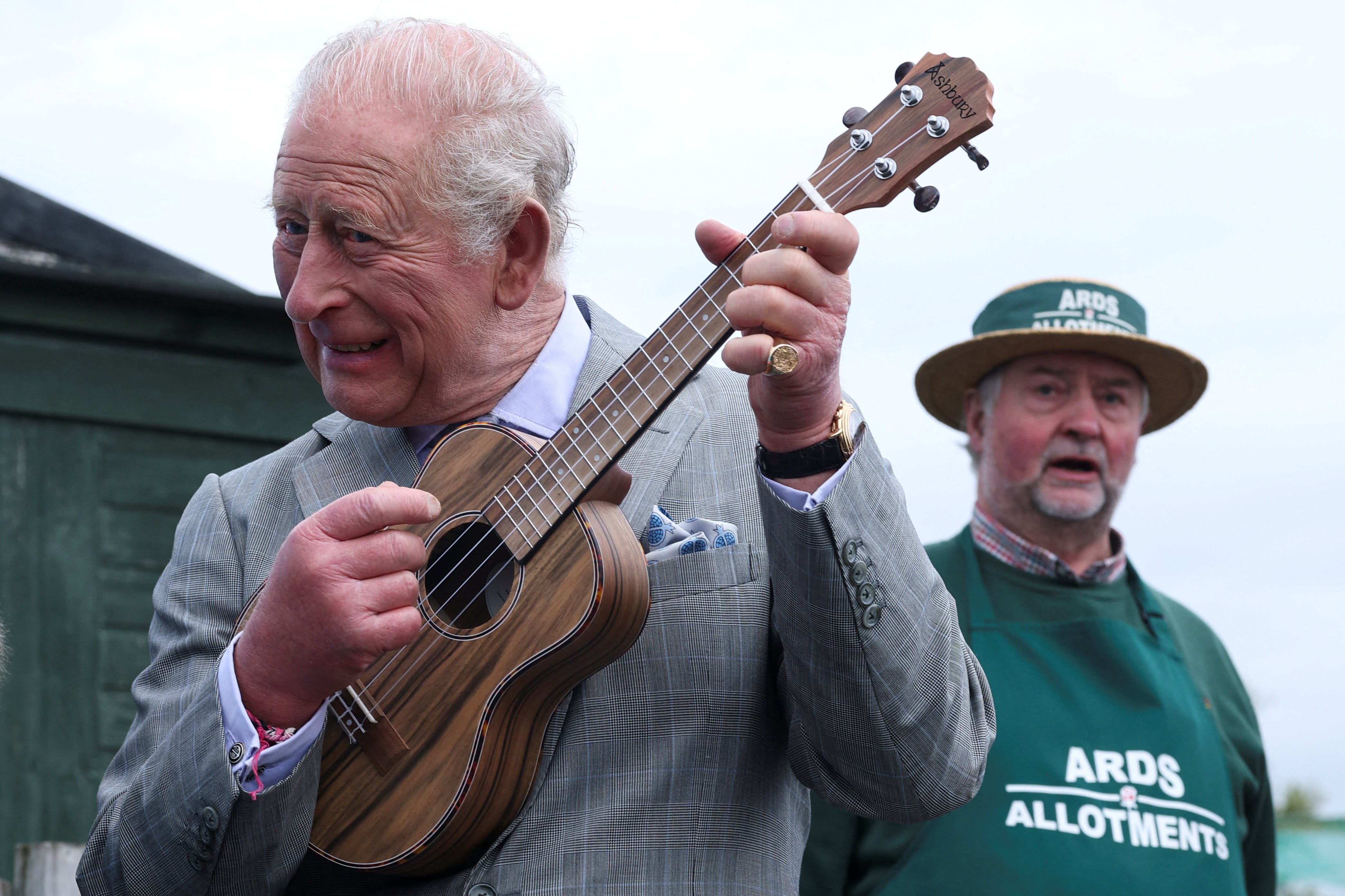 Charles played a ukulele while meeting members of the Loughries Men’s Shed Ukulele Ensemble at Ards Allotments (Toby Melville/PA)