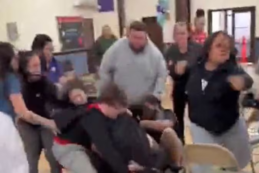 A woman allegedly attacked another woman at a kindergarten graduation at Queen of Apostles School Thursday, grabbing her hair and slamming her head into a chair, causing injuries requiring stitches
