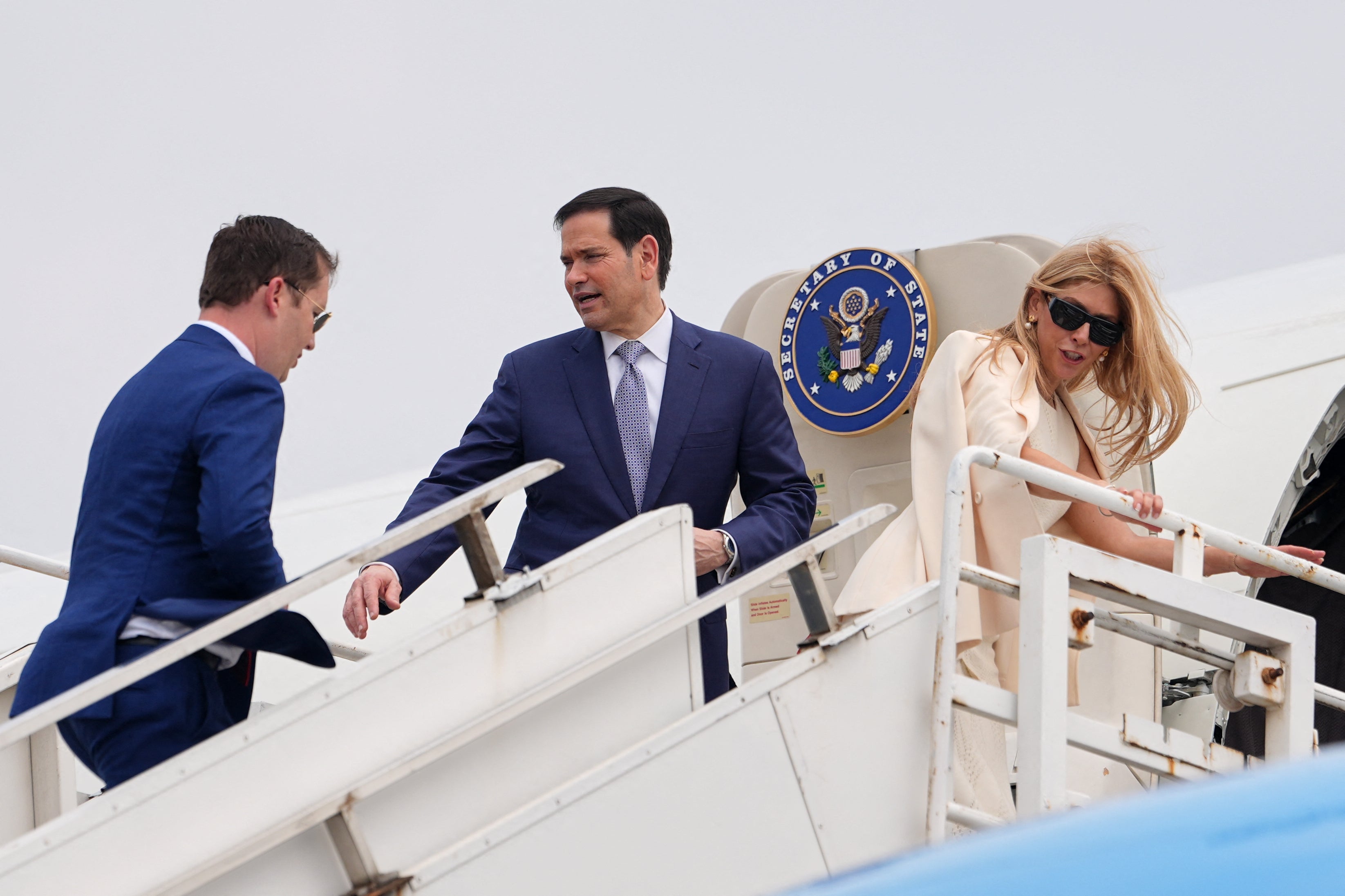 US Secretary of State Marco Rubio (C) gestures to the US Ambassador to India Sergio Gor as they board their plane for New Delhi at Netaji Subhash Chandra Bose International Airport in Kolkata