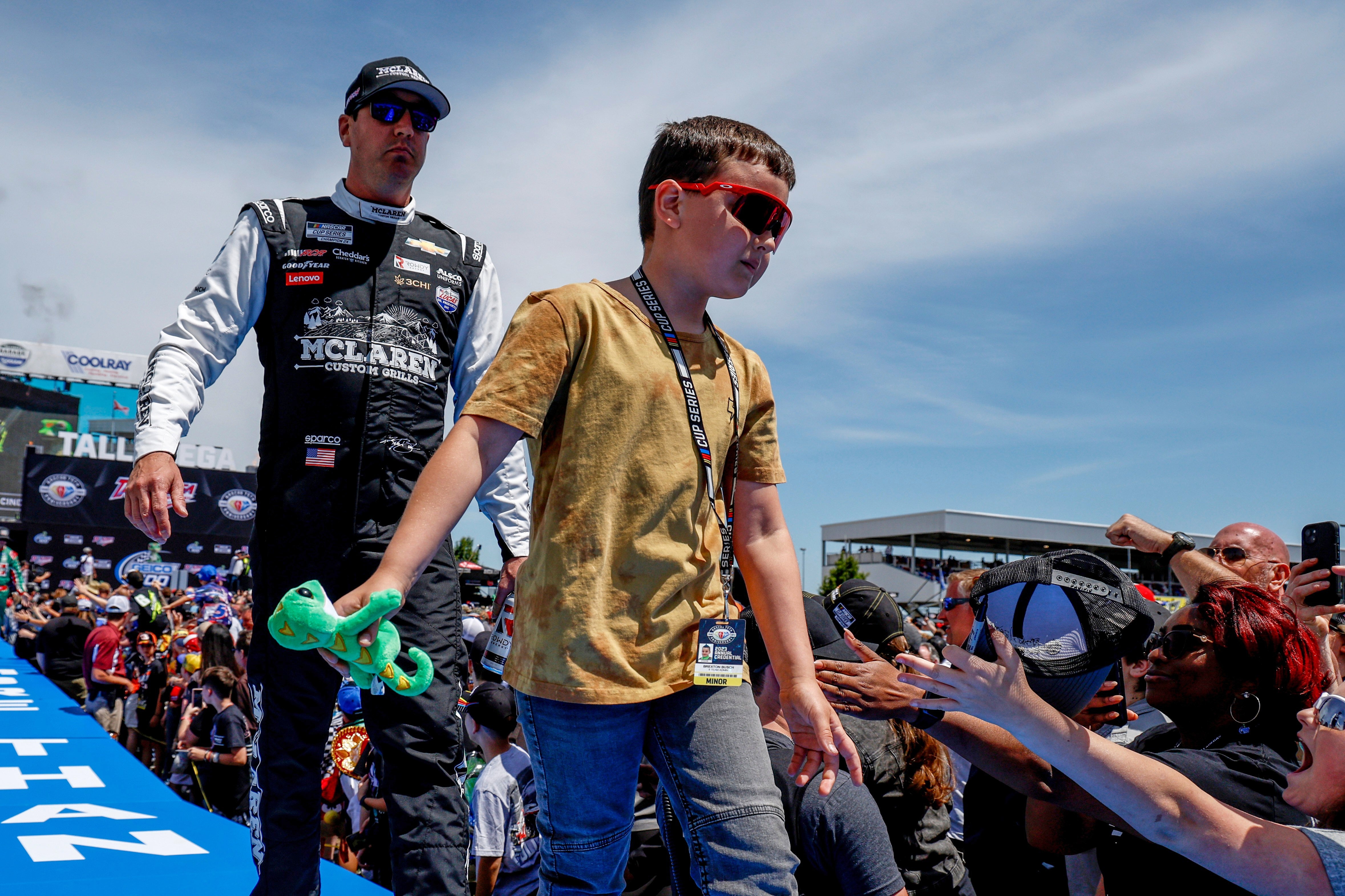 The late Kyle Busch and his son greet fans before a NASCAR Cup Series auto race at Talladega Superspeedway, April 23, 2023 (AP Photo/Butch Dill)