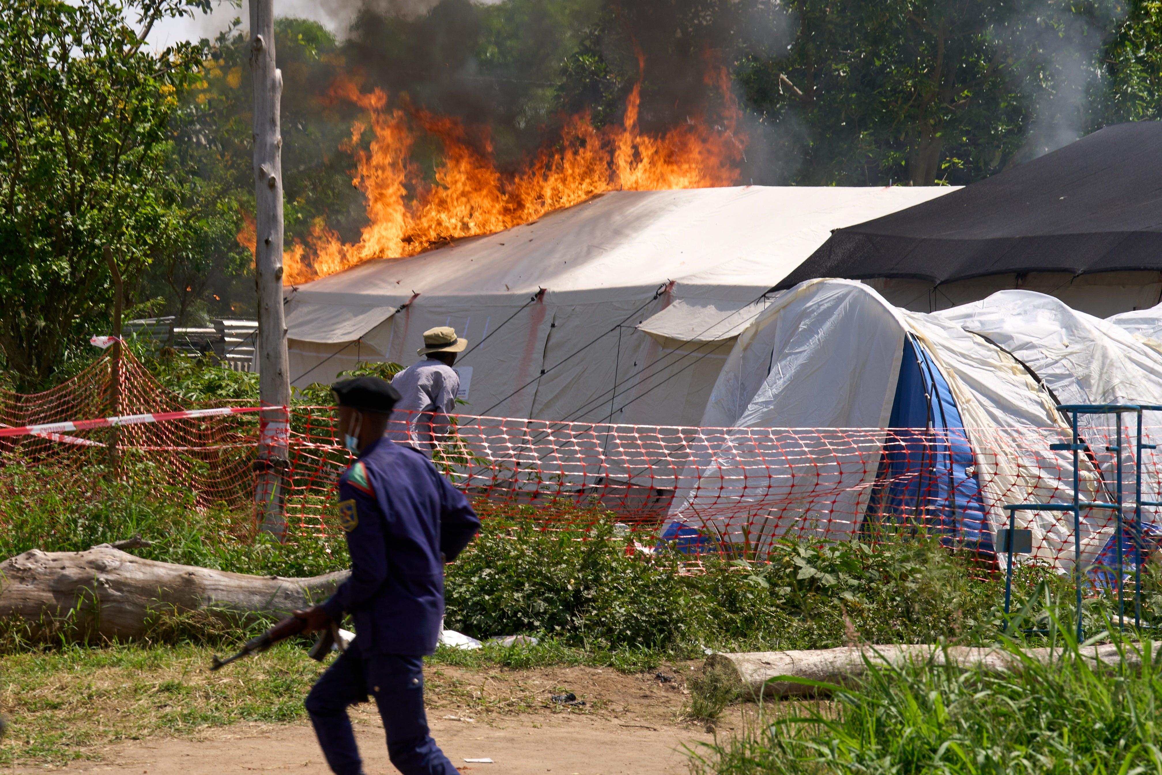 A security guard runs in front of an Ebola treatment center in flames in Rwampara, Congo, Thursday, May 21, 2026