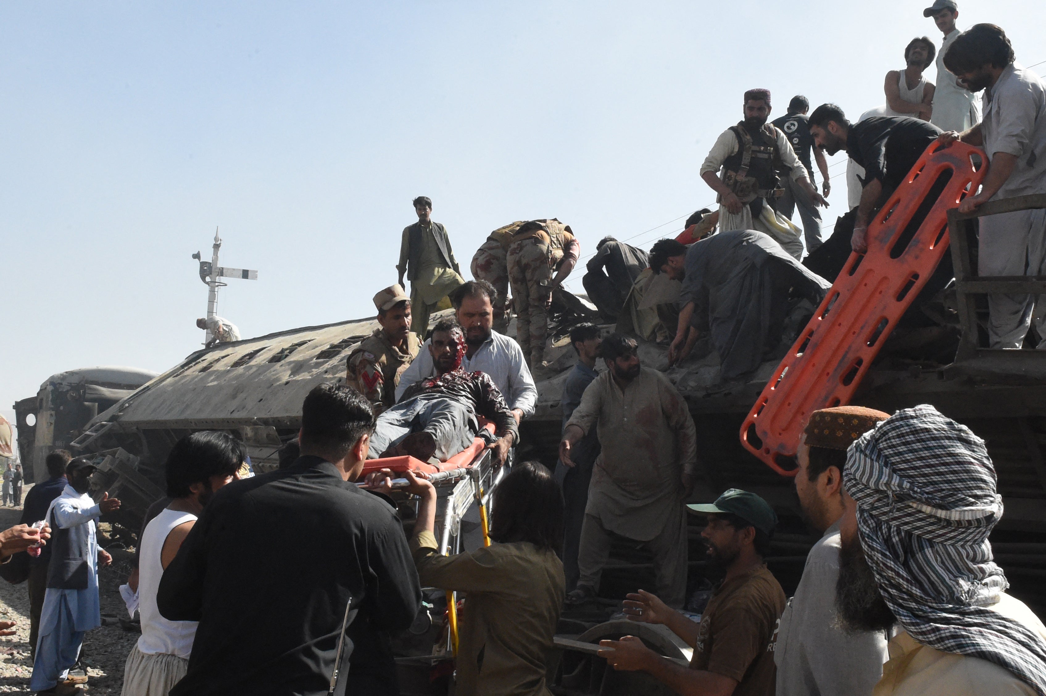 Security personnel and residents rescue injured blast victims from derailed carriages