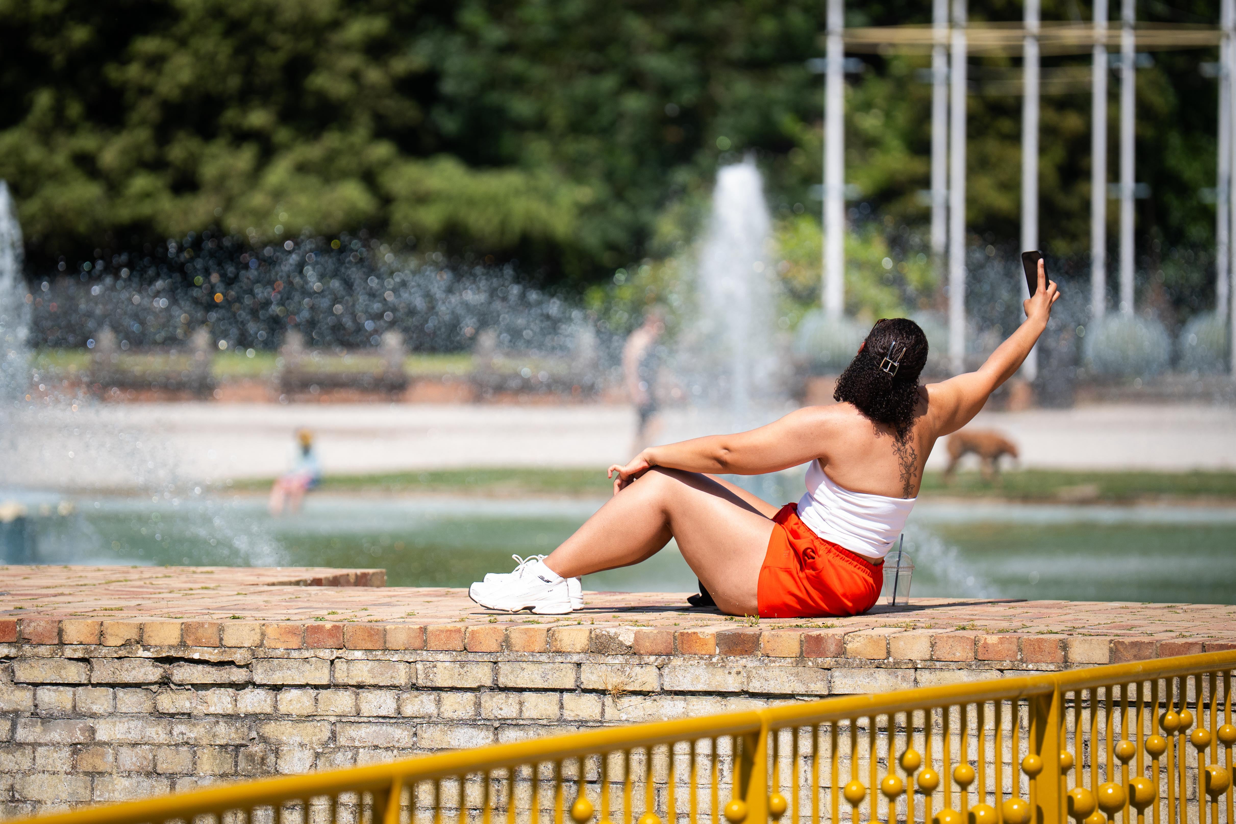 A person sun bathes near water fountains in Battersea Park, south west London (PA)
