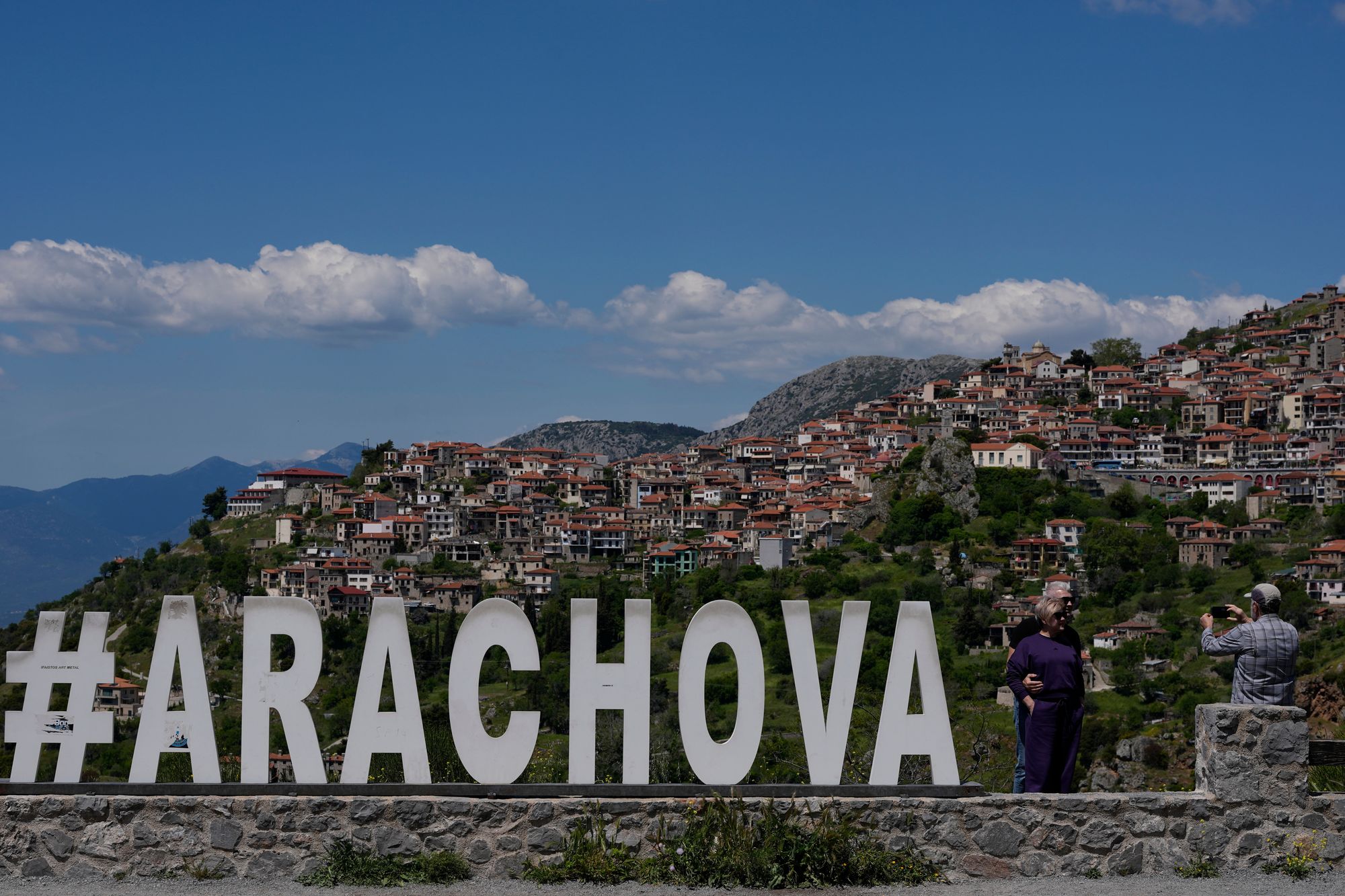 Tourists take photos with the popular winter resort town of Arachova in the background, central Greece