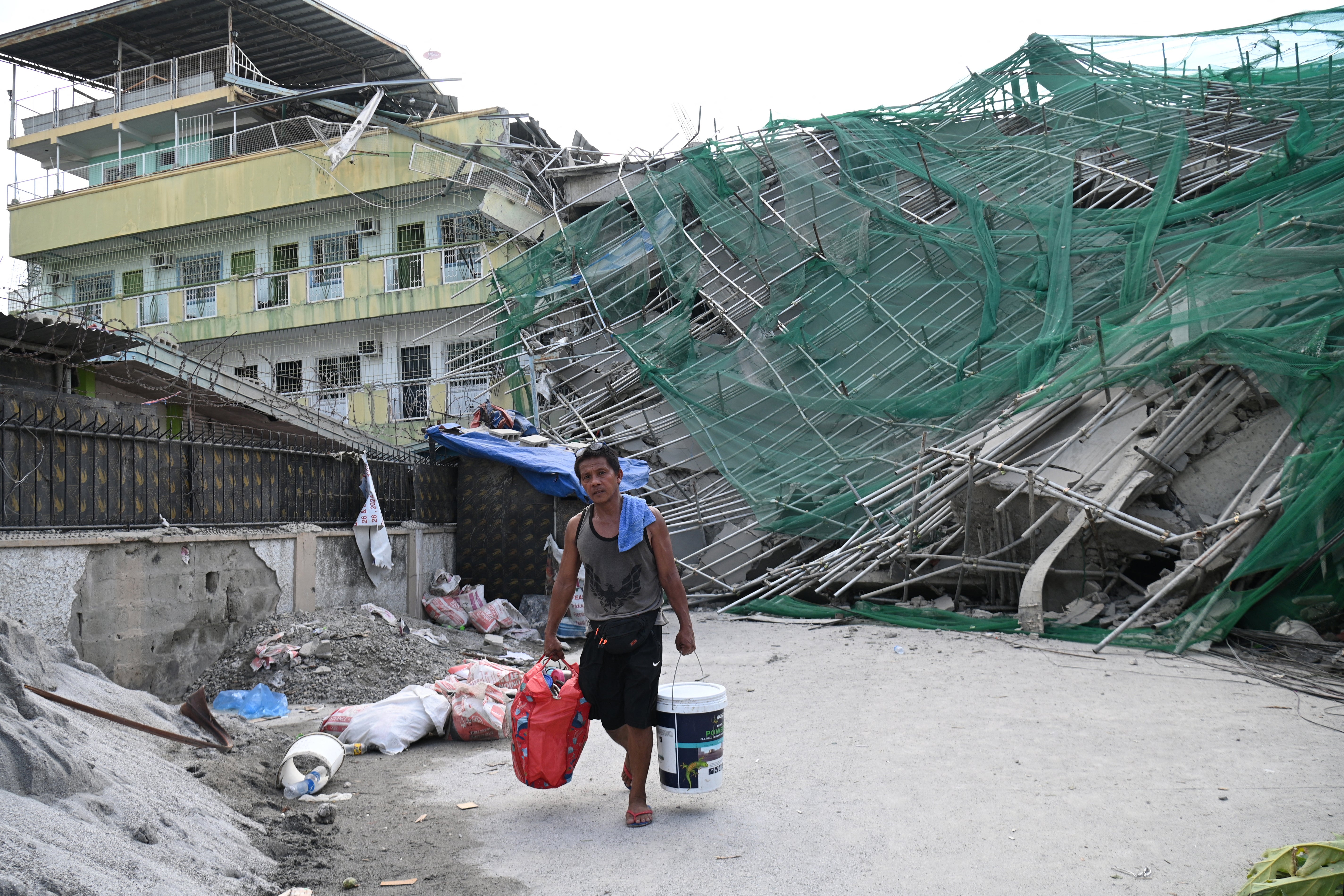 A worker carries belongings retrieved from a collapsed building in Angeles City on 25 May 2026