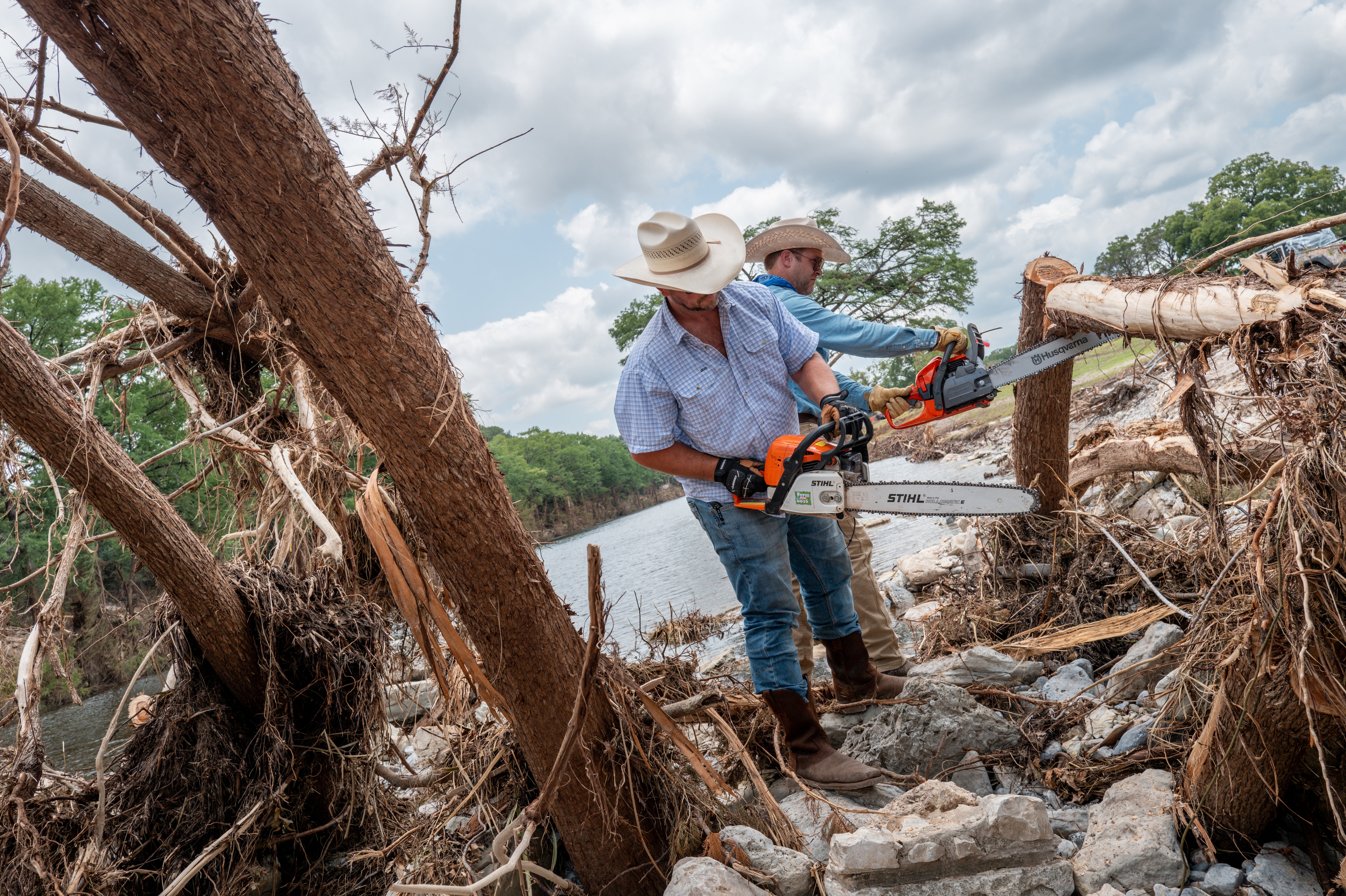Volunteers Zak Coppinger and Bryan Bailey work to clear fallen trees in the wake of deadly flash floods in Hunt, Texas, last July. More flash floods are forecast in the area this summer