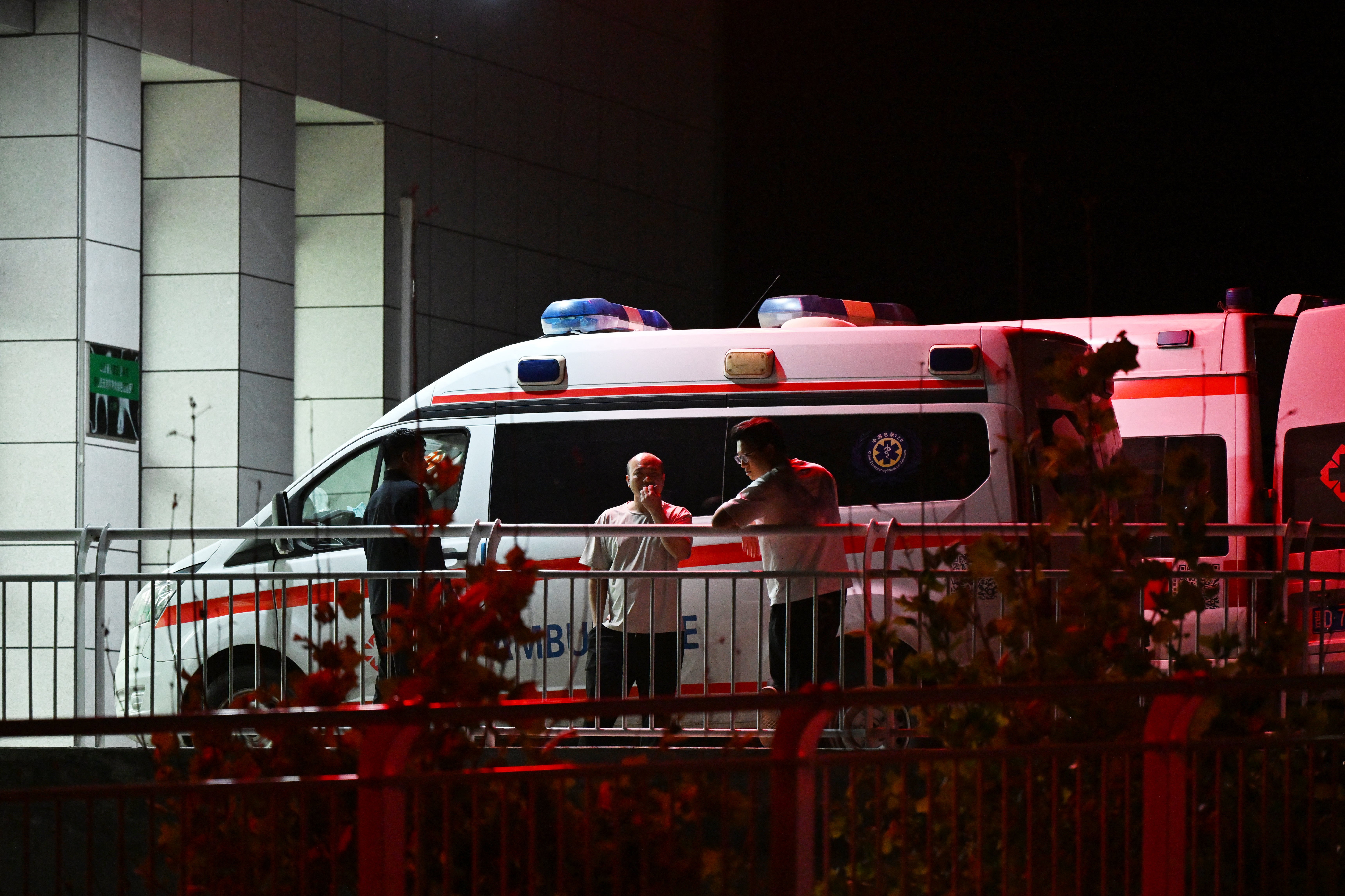 Men stand beside ambulances at the cordoned-off Qinyuan People's County Hospital, 20 km from the Liushenyu coal mine, where dozens of workers were killed in an explosion, in Qinyuan county, in China's northern Shanxi province on 24 May 2026