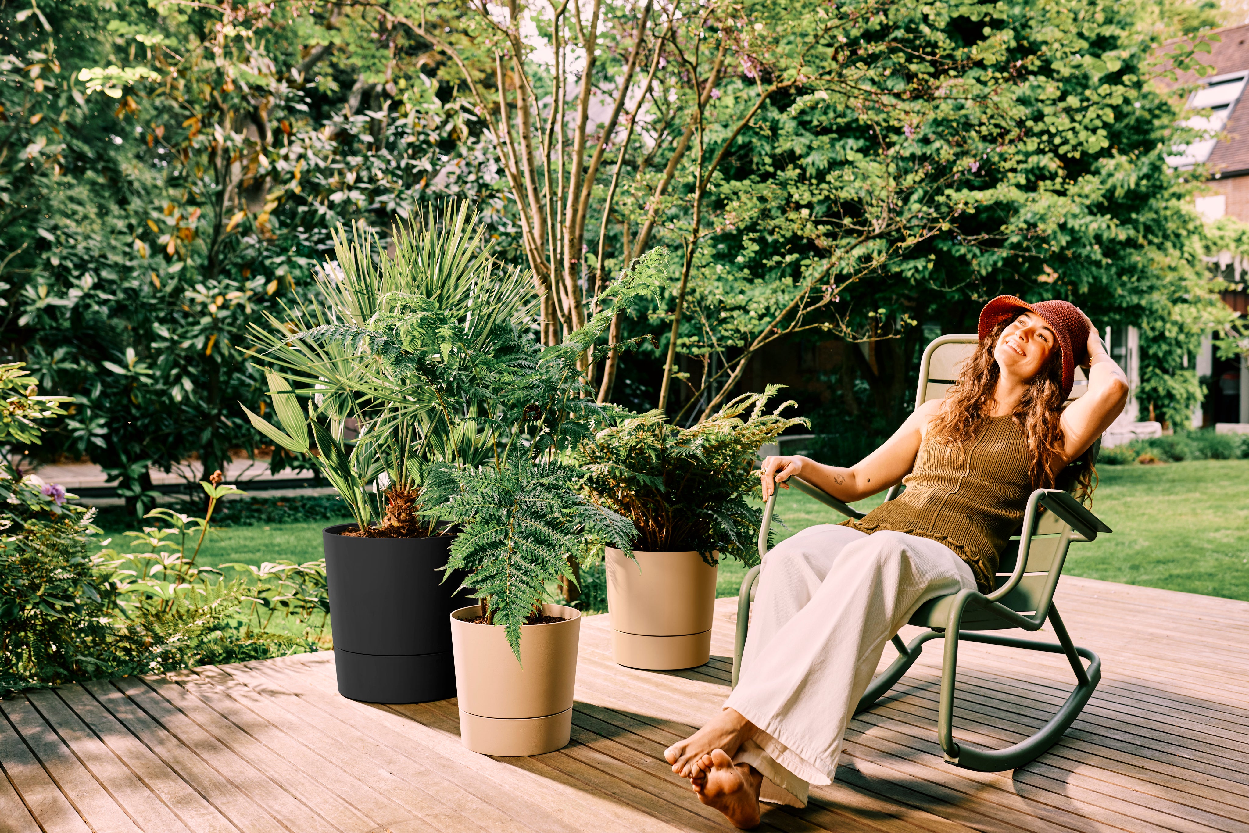 A woman on garden decking with Elho foss pots with reservoirs (elho/PA)