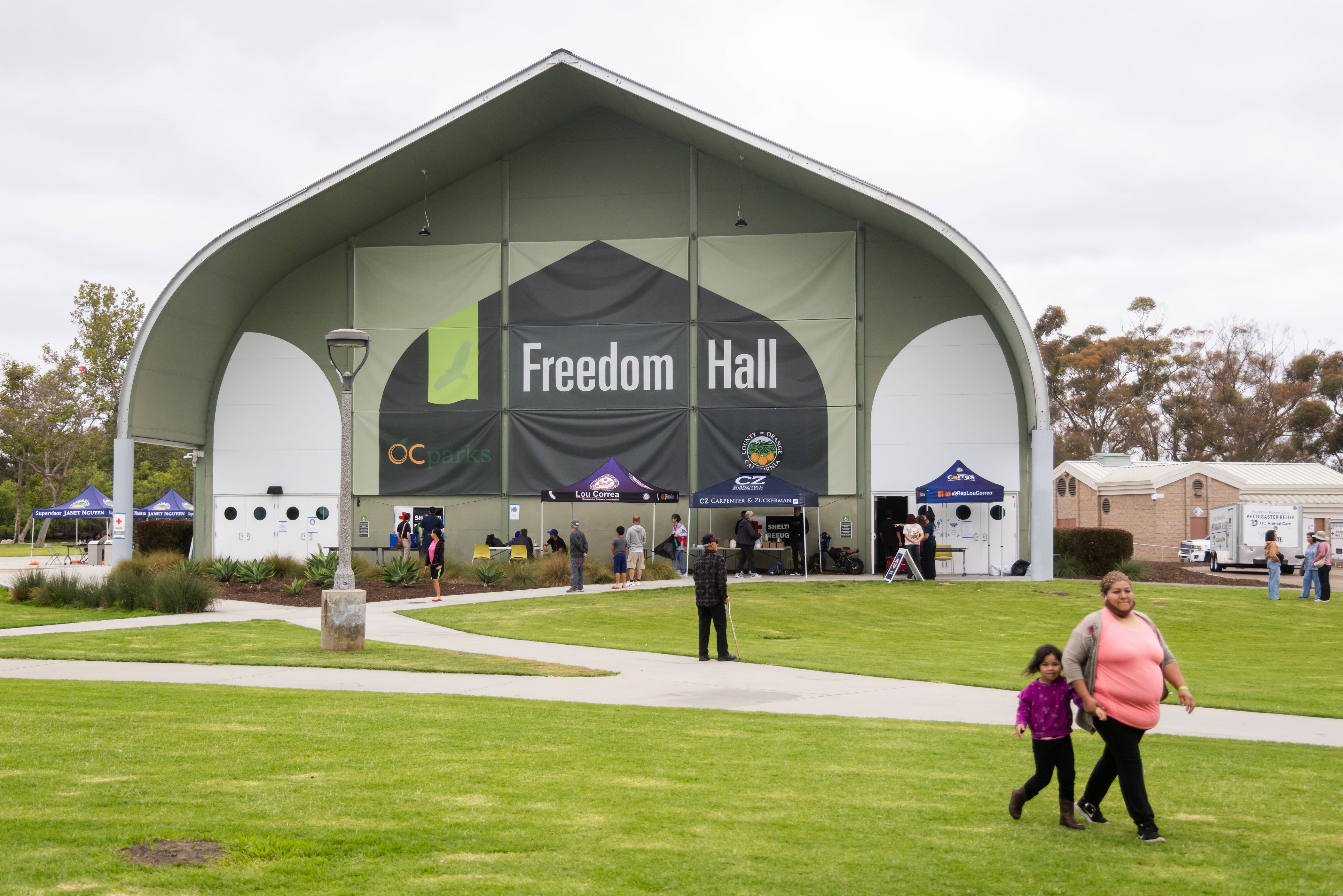People walk outside Freedom Hall, an evacuation center in Fountain Valley, California