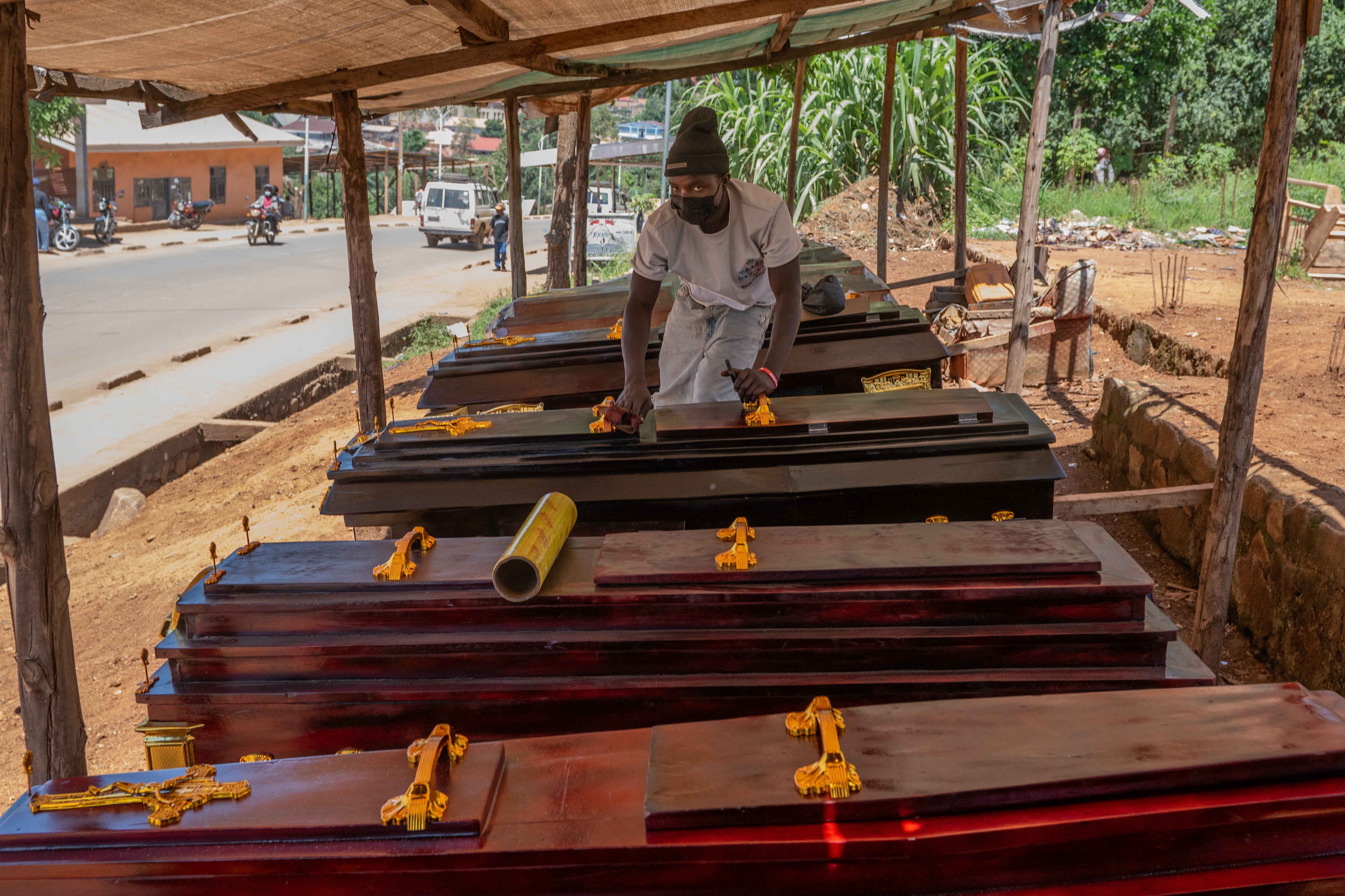 Djakisa Christian, 18, a funeral home manager, dusts coffins for sale at his shop in Bunia, Congo
