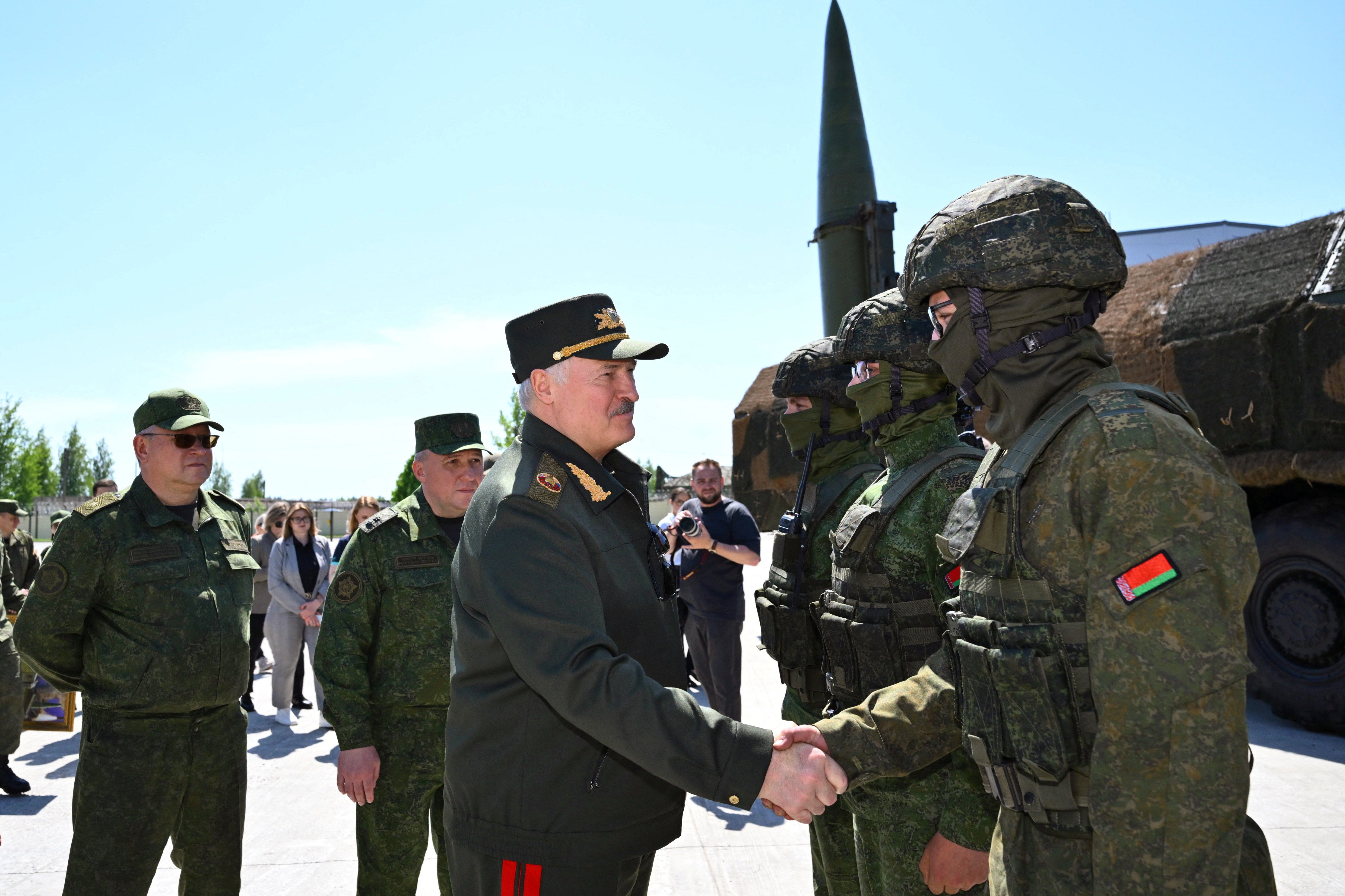 Belarusian President Alexander Lukashenko shakes hands with a service member next to the Iskander-M missile launcher as he visits a missile brigade of the Armed Forces during joint Russian-Belarusian nuclear exercises.