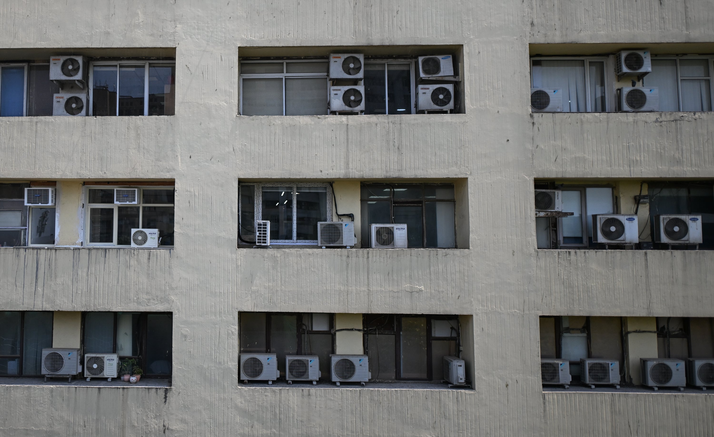 Air conditioning outdoor units are seen mounted on the exterior of a multi-storey building