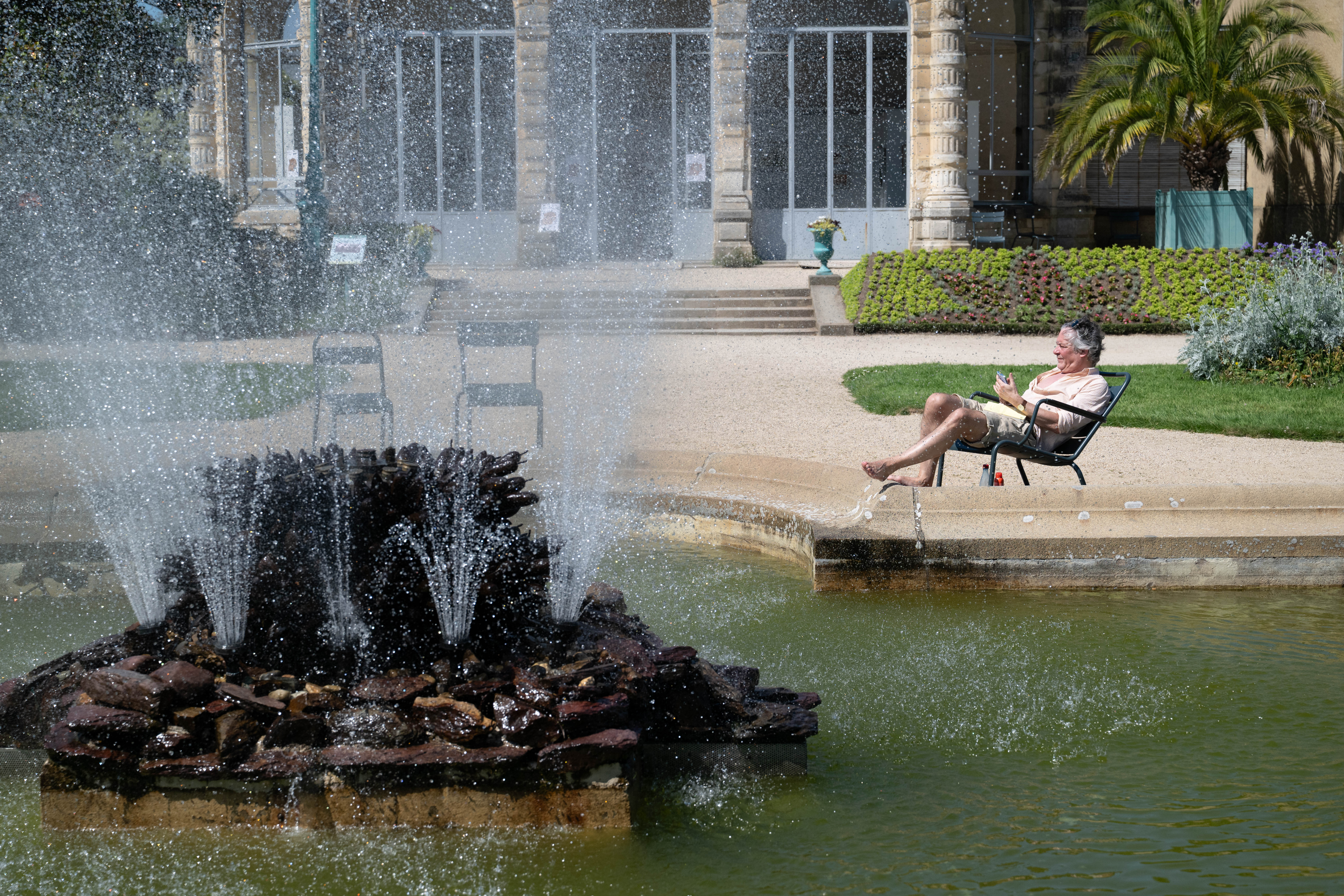 A man sits by a fountain at the Thabor park in Rennes, during a heatwave affecting western France on May 25