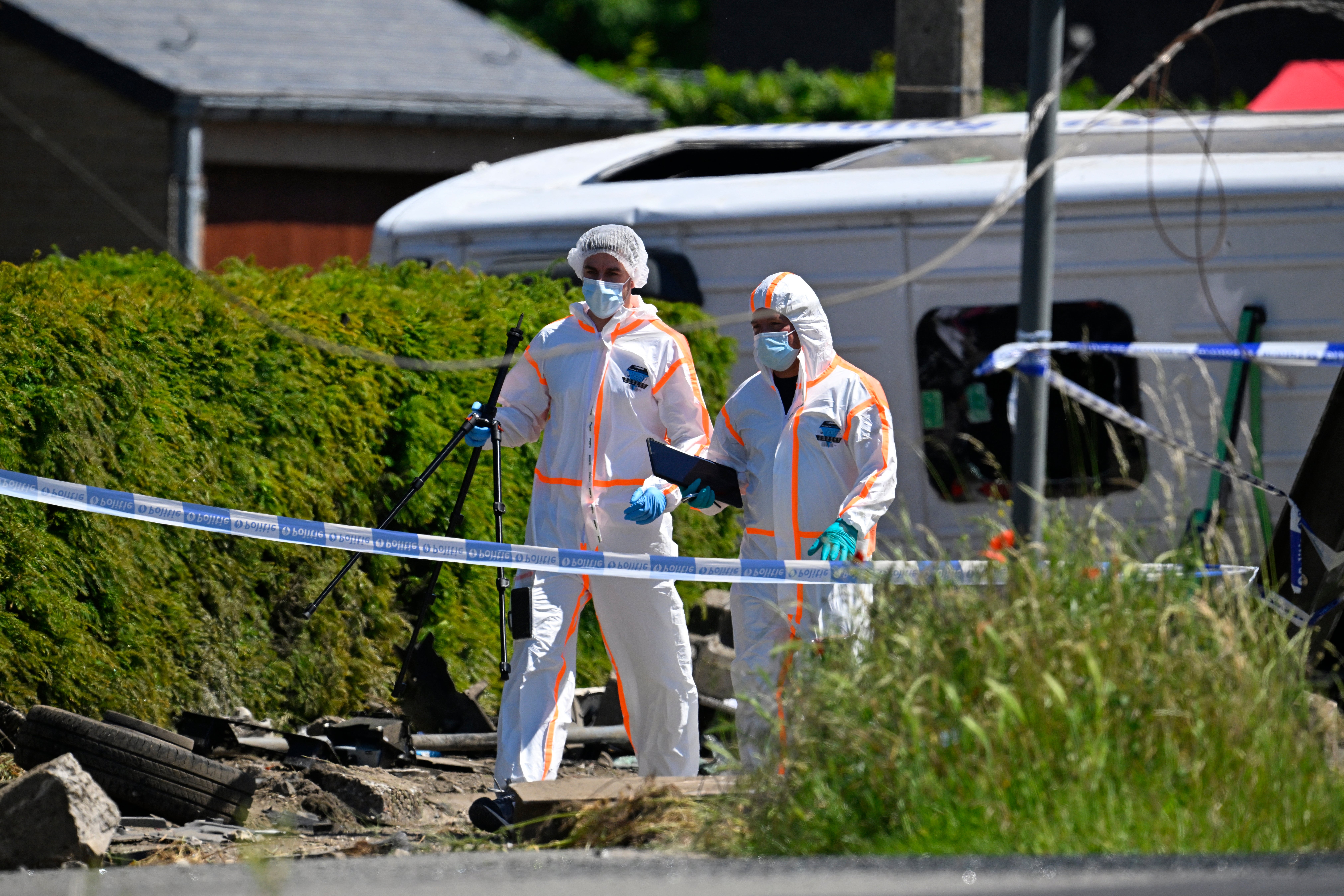 Forensic Police officers walk next to the damaged bus as they inspect at the site of an accident after a train crashed into a school bus, at the railway crossing Vierhuizen in Buggenhout (AFP/Getty)