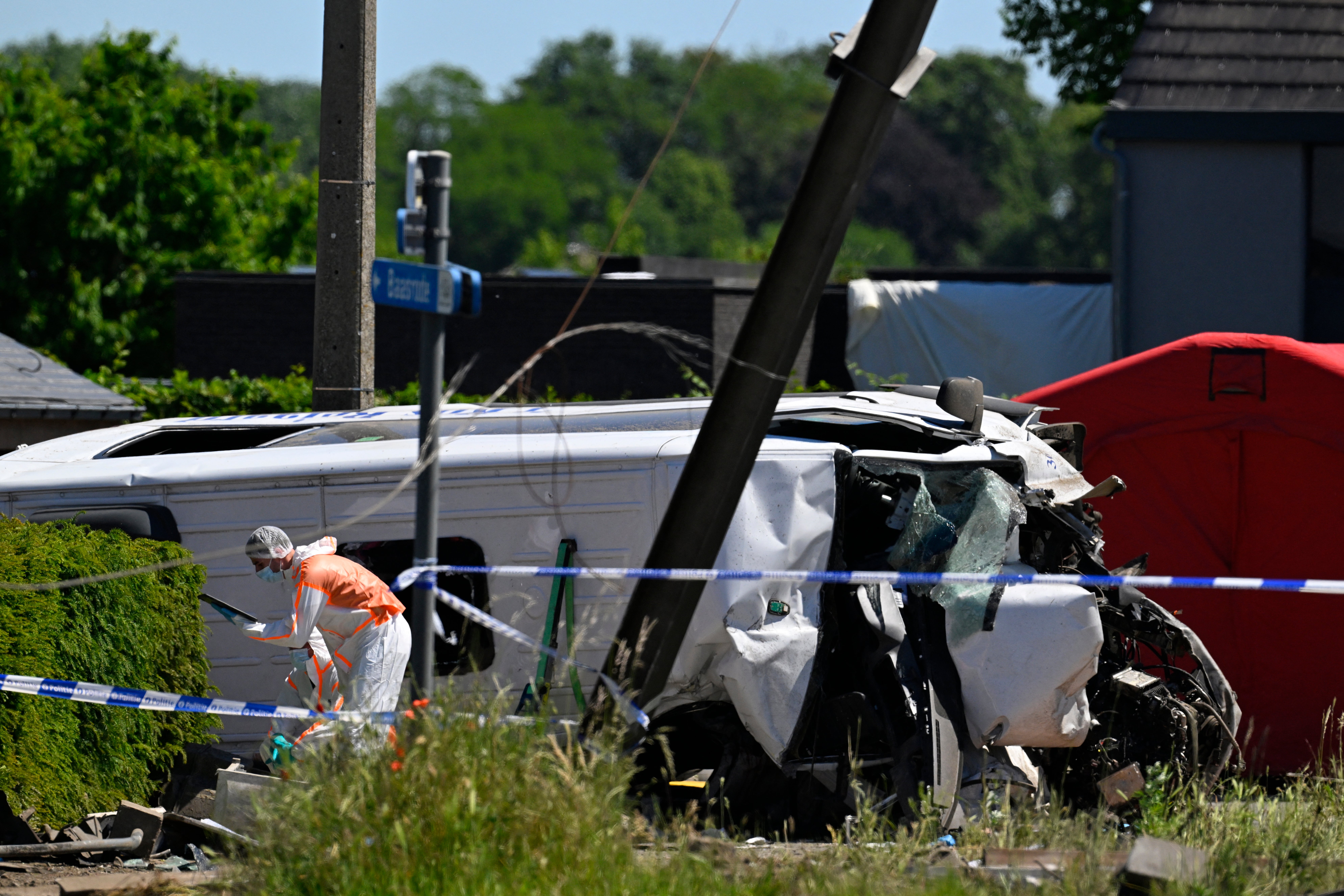 A Forensic Police officer inspects next to the damaged bus at the site of an accident after a train crashed into a school bus, at the railway crossing Vierhuizen in Buggenhout (AFP/Getty)
