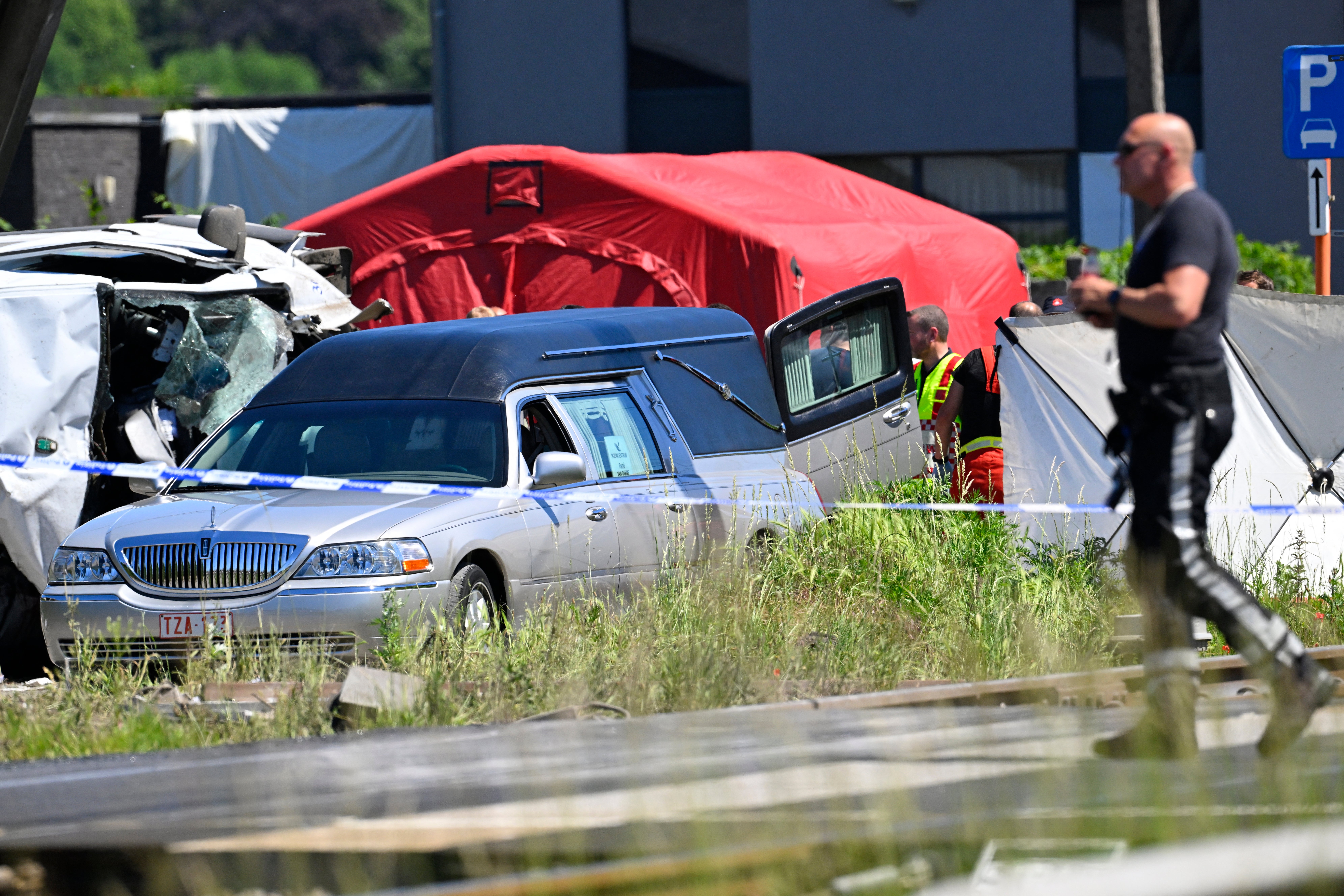 A hearse is parked next to the crashed bus at the site of an accident after a train crashed into a school bus, at the railway crossing Vierhuizen in Buggenhout
