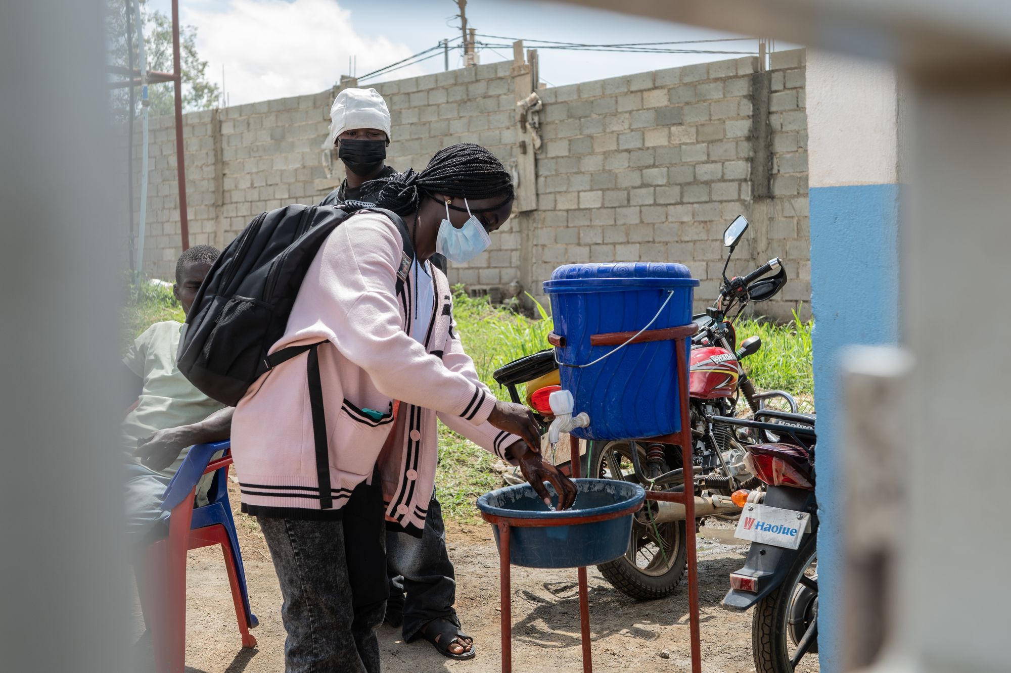 A young woman washes her hands before entering Bunia General Hospital
