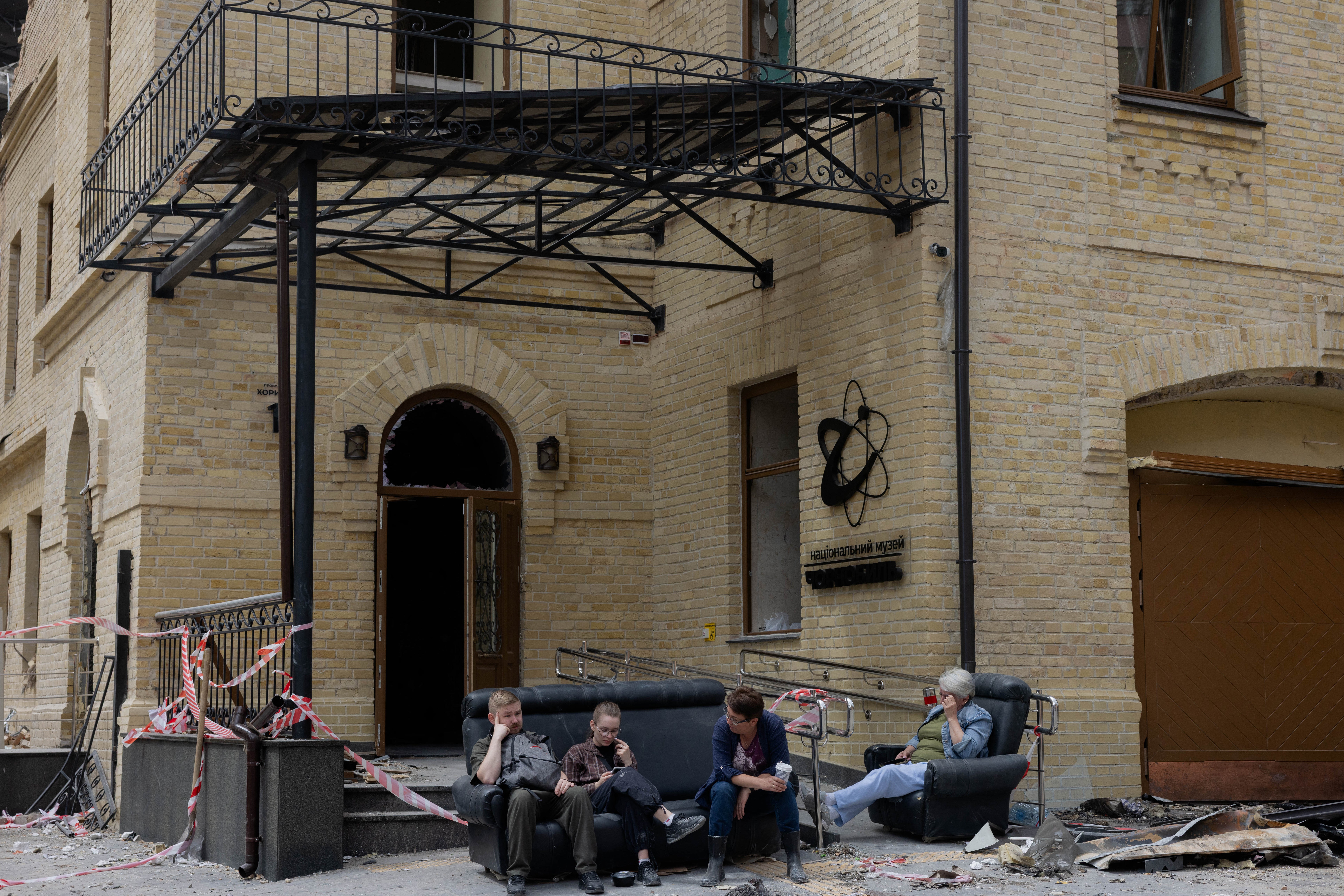 People sit on a sofa in the street outside the damaged building of the Ukrainian National Chernobyl Museum (AFP/Getty)