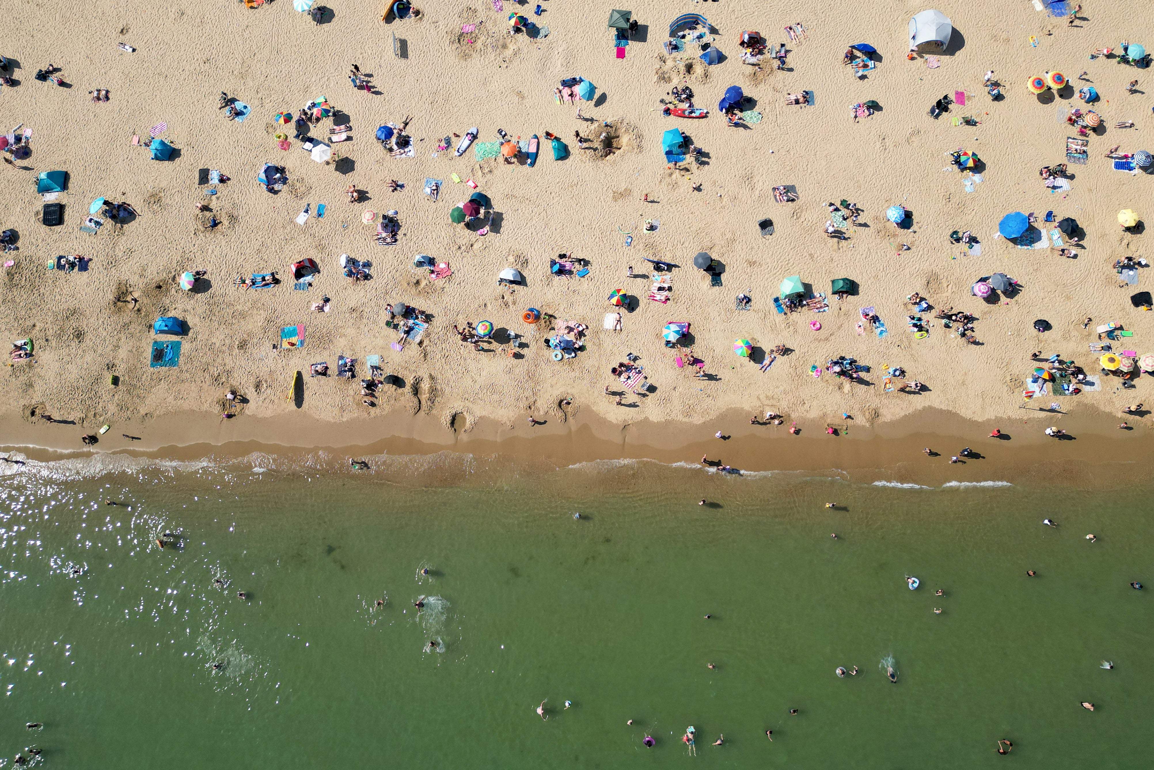 People playing in the sea and relaxing in the sunshine on Bournemouth beach on the south coast of England on May 26
