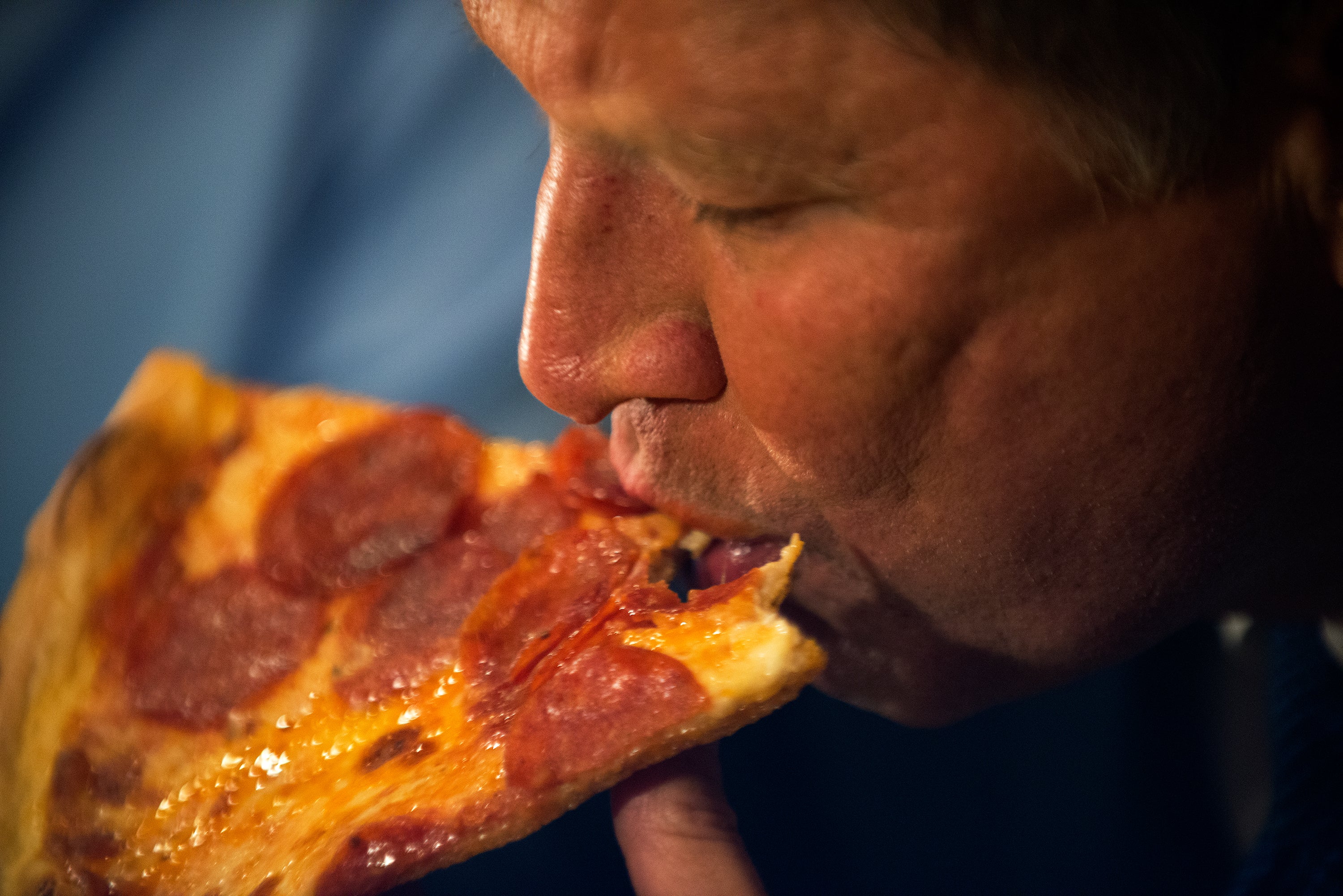 Former GOP Presidential Candidate John Kasich eats a piece of pizza at Gino's Pizzeria and Restaurant in New York City in March 2016. Pizza is one of the ultraprocessed foods most binged over the last few decades (Getty)