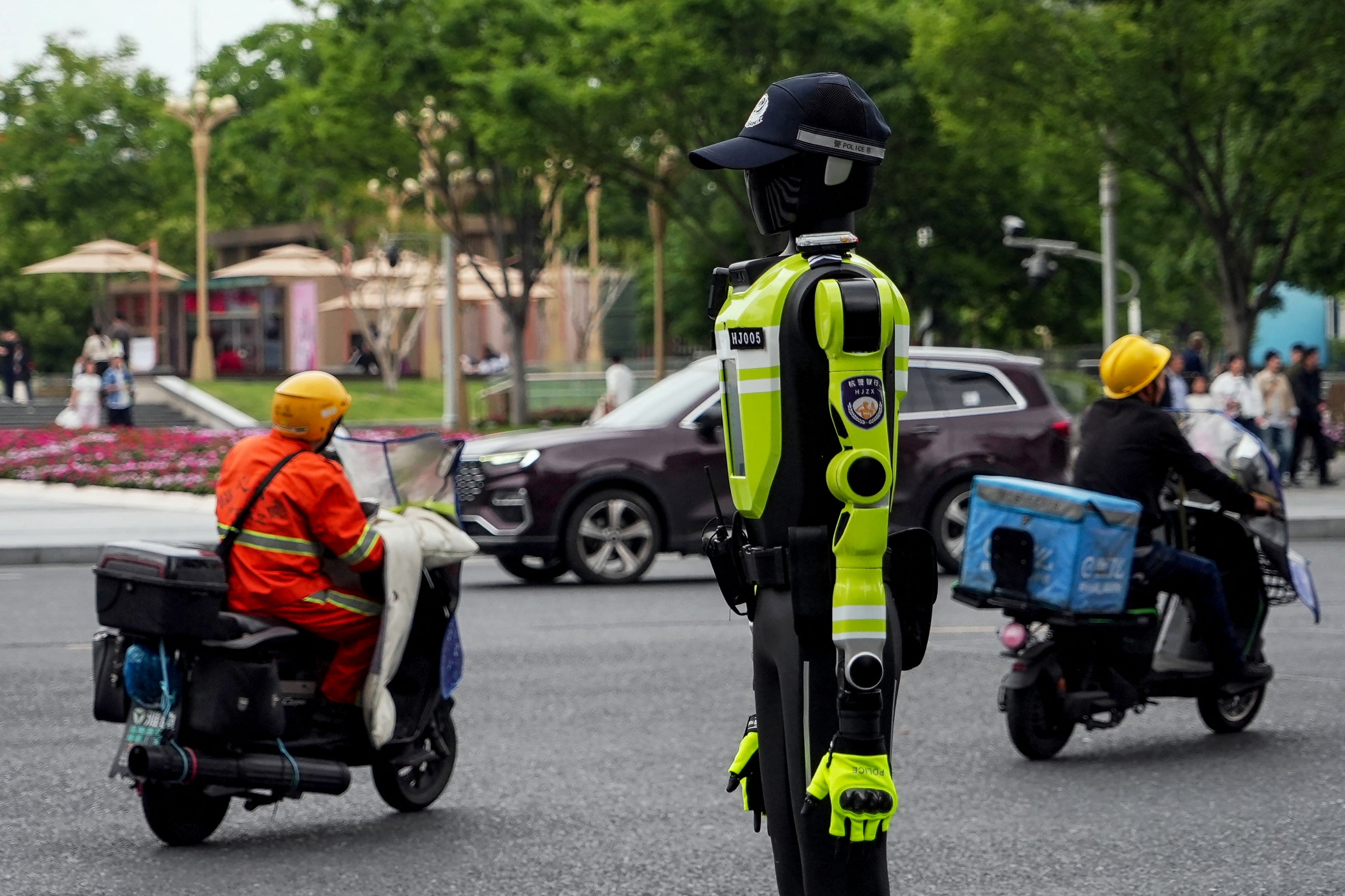 People ride past a humanoid robot police officer in Hangzhou