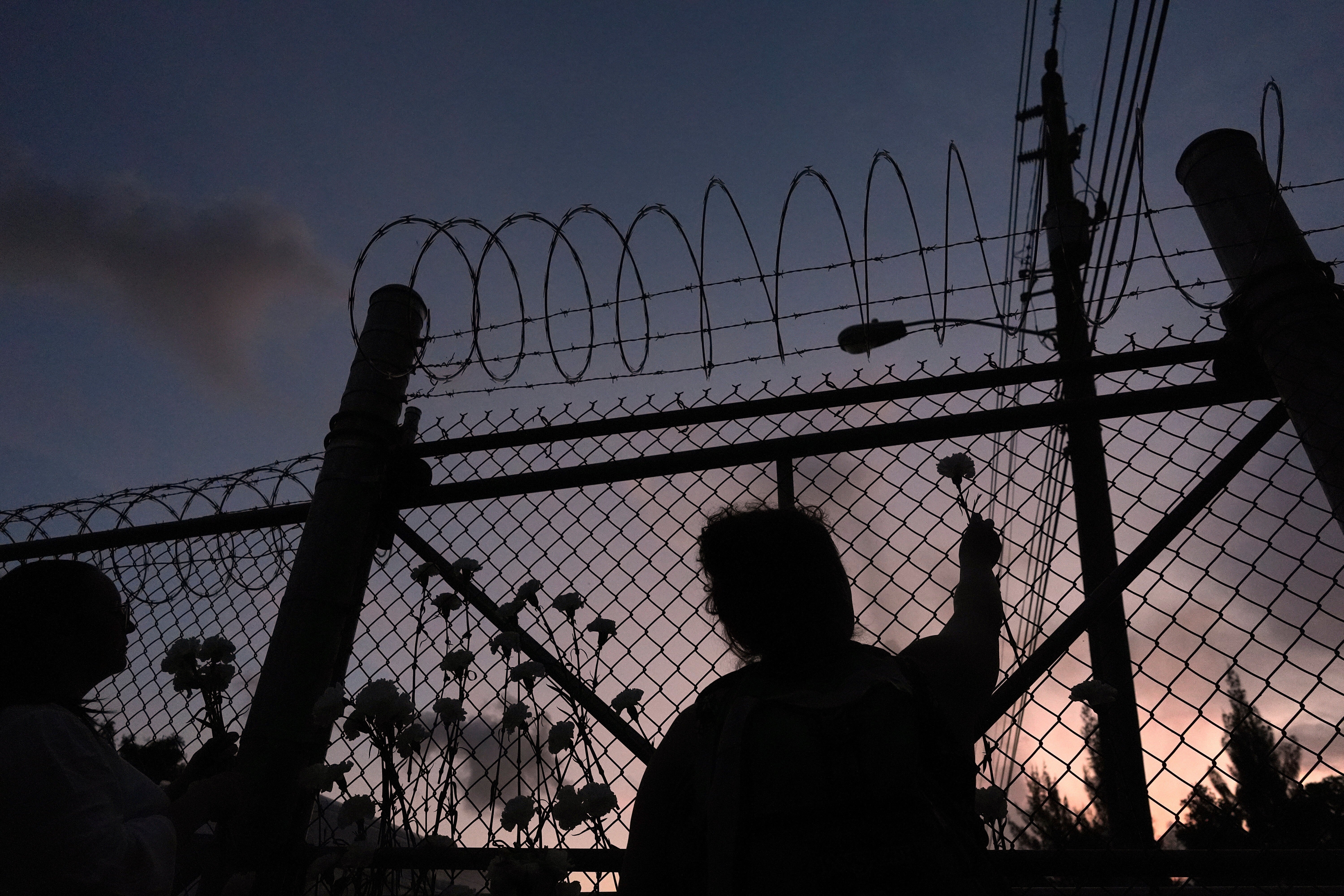People place flowers on a fence outside Krome Detention Center in Miami, Saturday, May 24, 2025, during a vigil to recognize people who have died in U.S. Immigration and Customs Enforcement custody