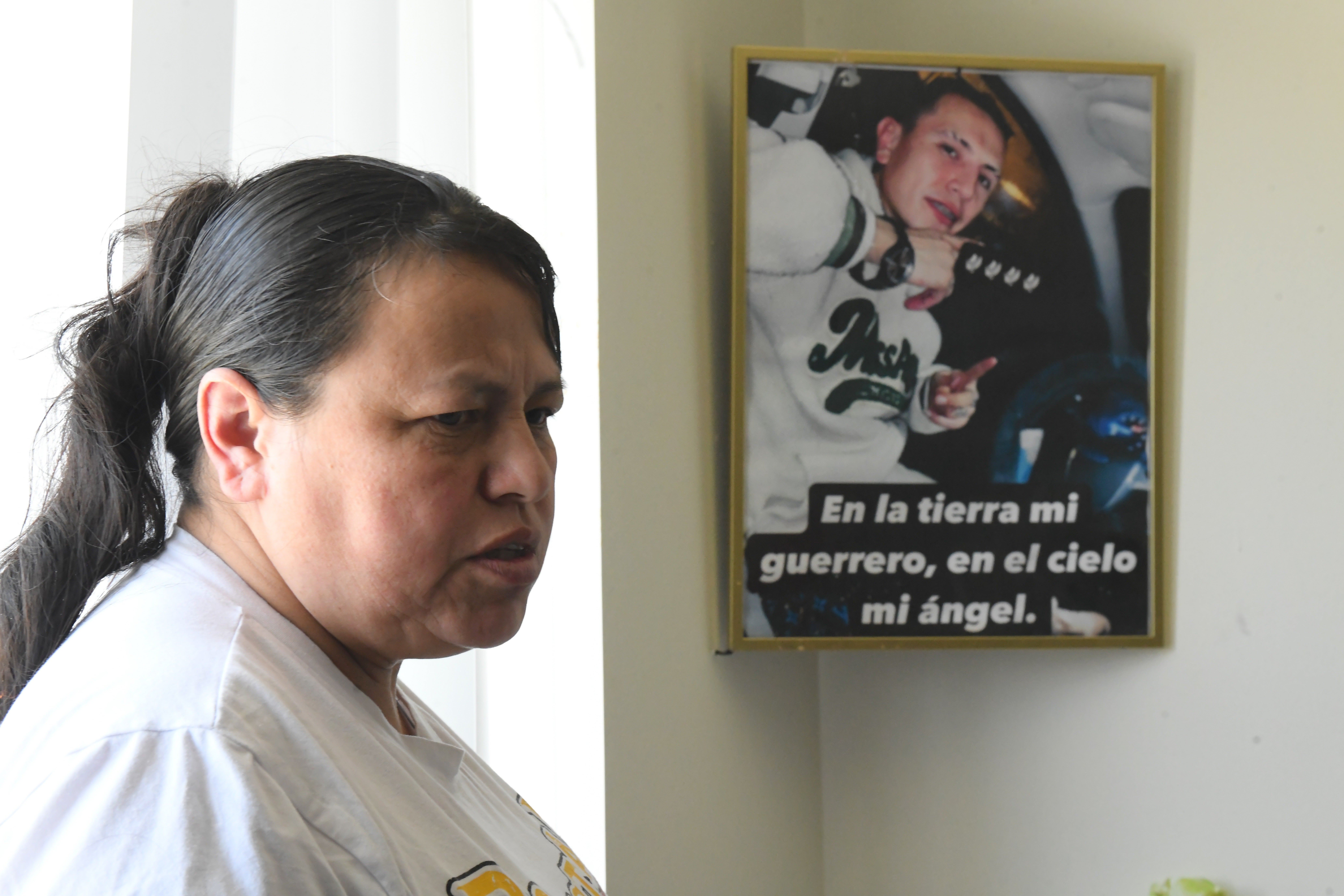 Adriana Garzon, mother of Brayan Rayo Garzon who died by suicide while in ICE custody in April 2025, stands next to a photo of Rayo that reads "On earth, my warrior; in heaven, my angel"