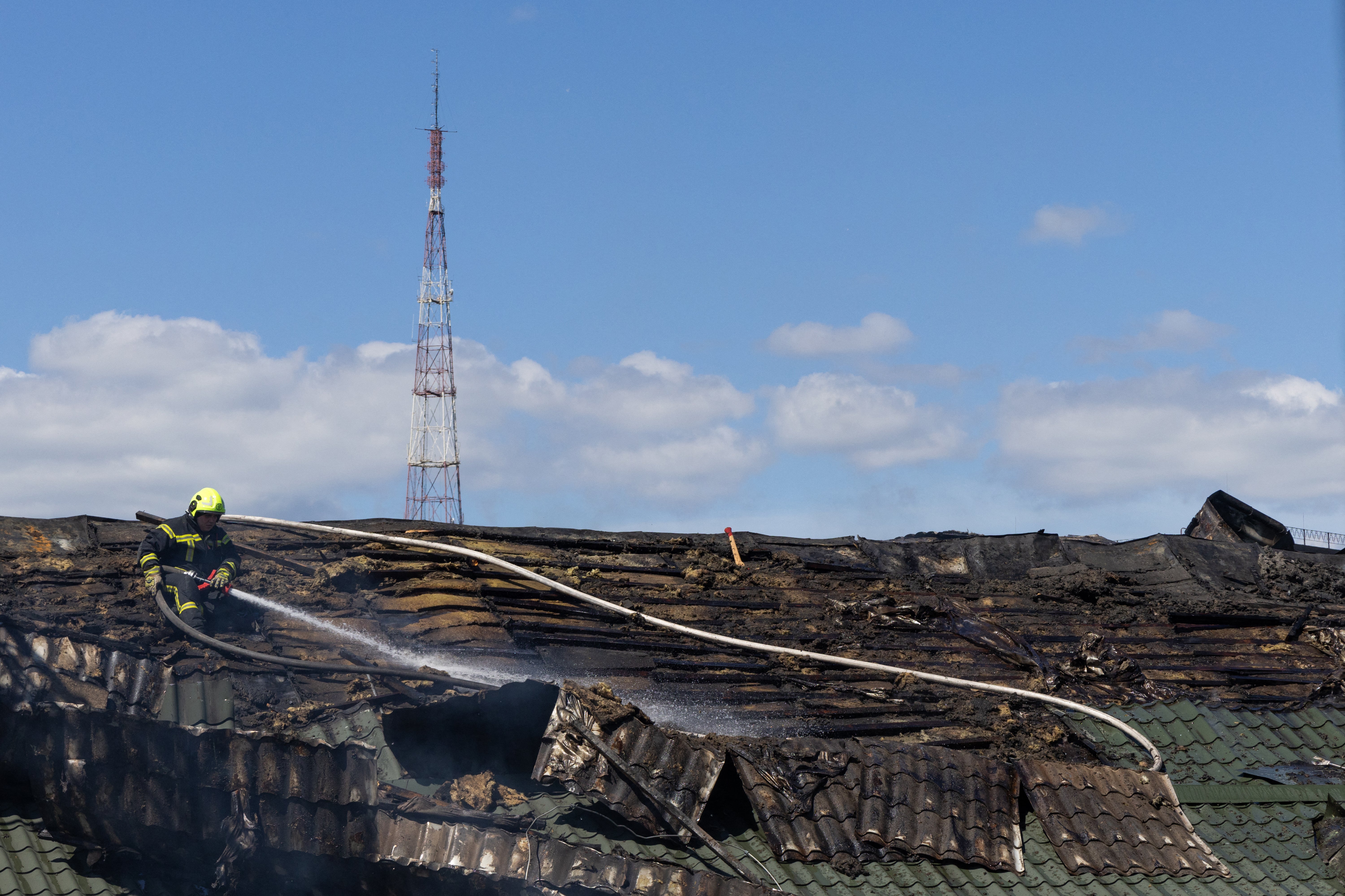 A firefighter uses a hose on smoldering remnants on the roof of the National Chernobyl Museum, heavily damaged by an overnight Russian airstrike, in Kyiv