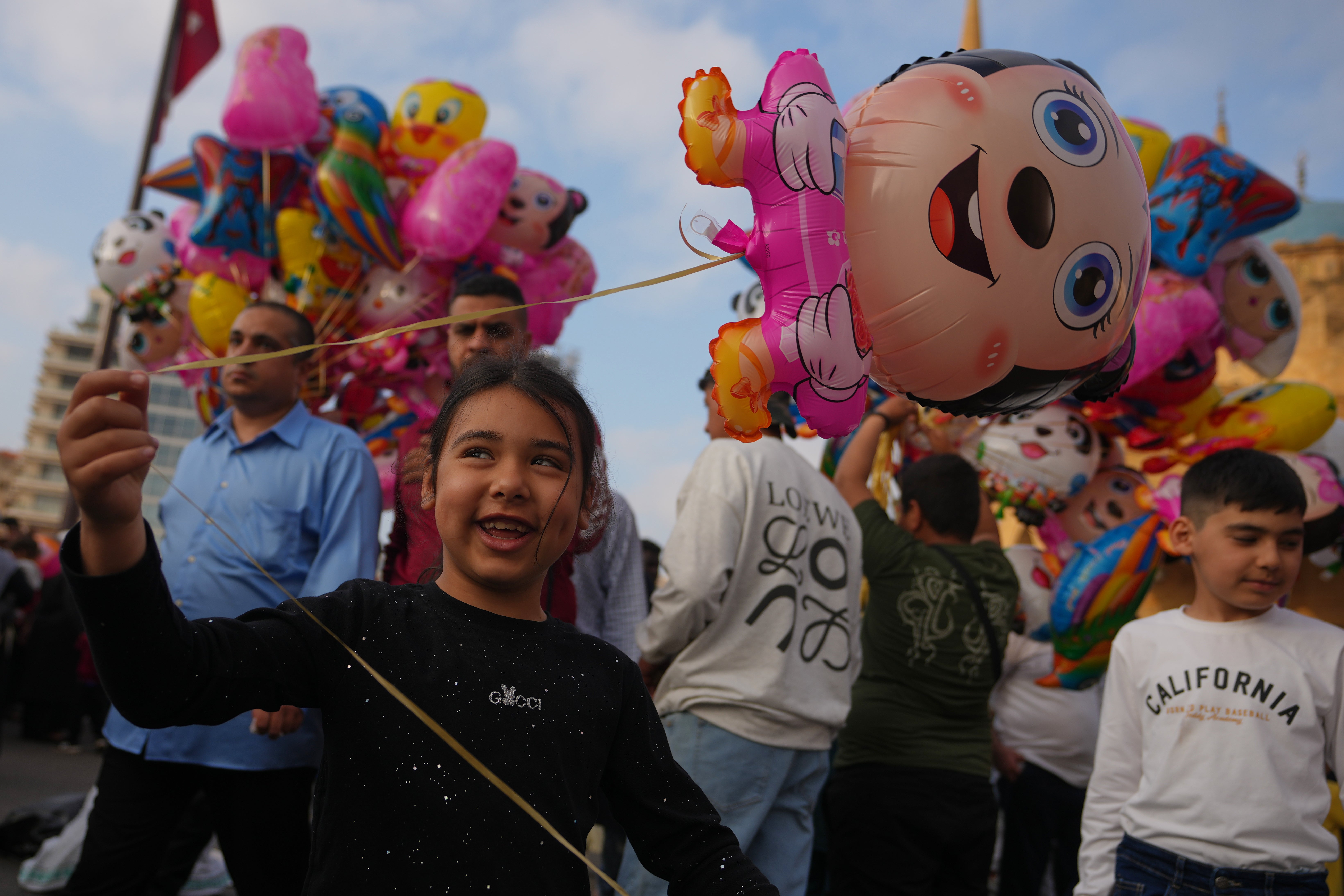 A girl holds a balloon as she celebrates Eid al-Adha with her family after Eid prayers outside Mohammad Al-Amin Mosque in Beirut, Lebanon, Wednesday, 27 May 2026