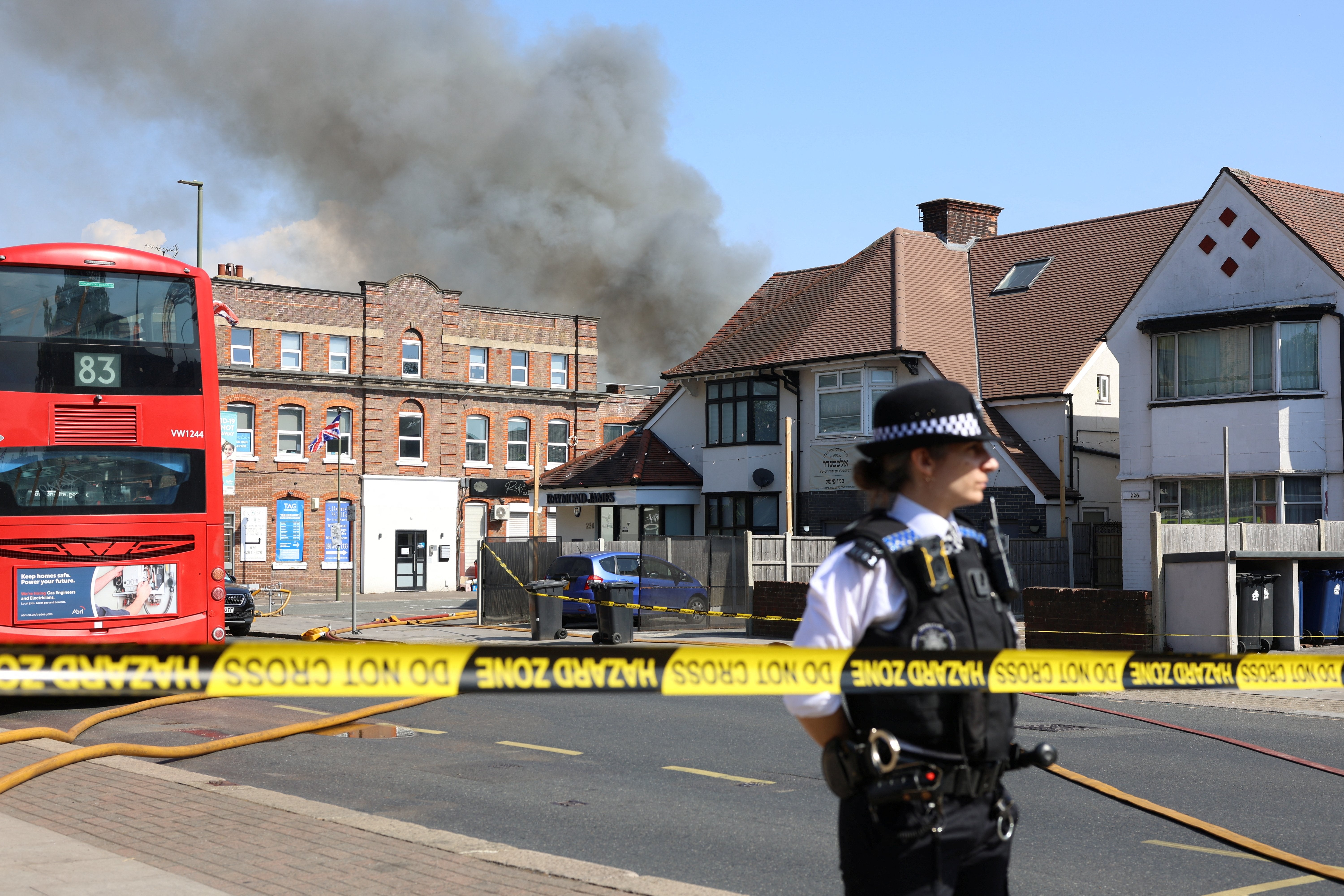 A member of the police stands at a cordoned area as smoke rises in the background (AFP/Getty)