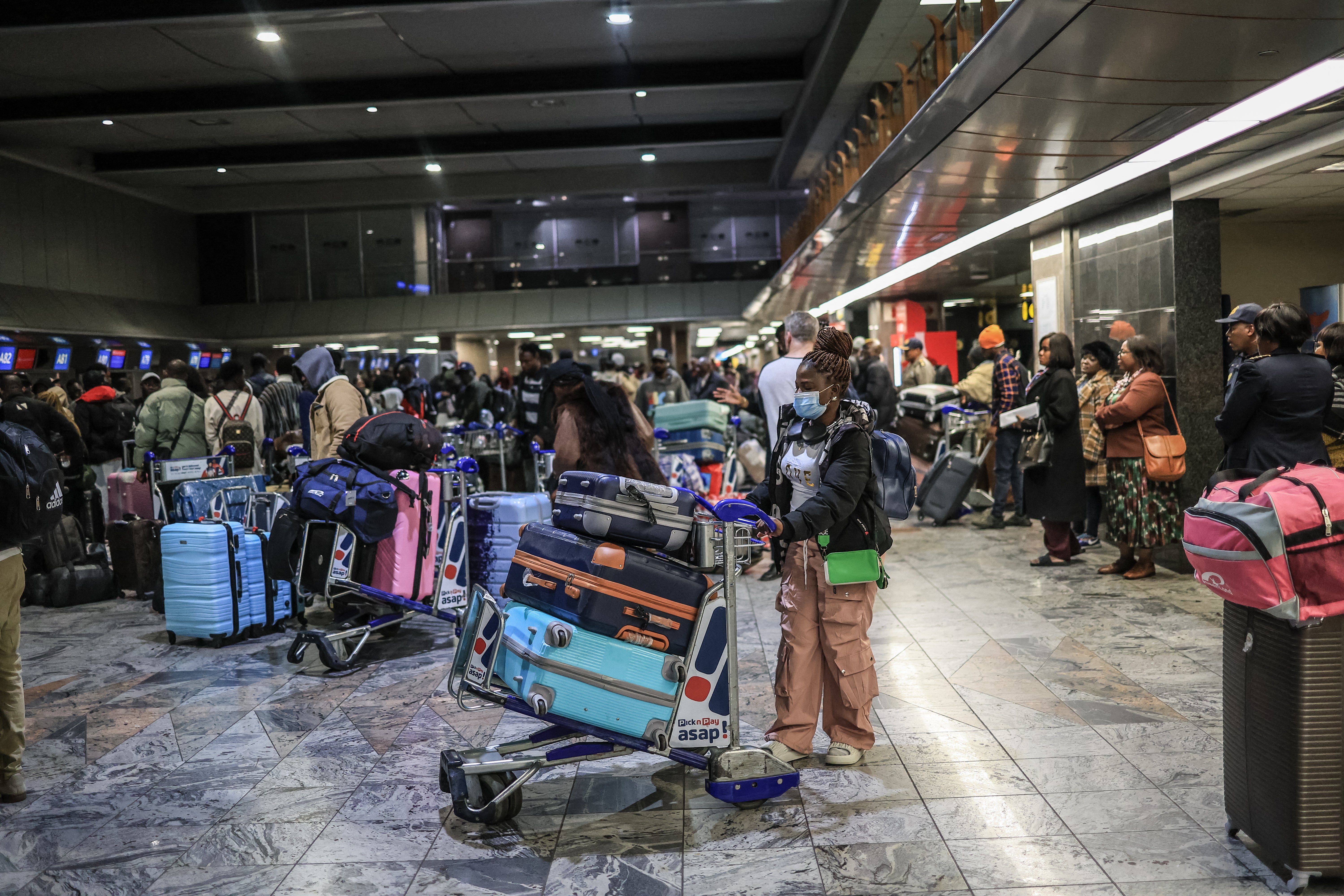 Ghanaian nationals stand at the check-in desk for an evacuation flight at OR Tambo International Airport in Ekurhuleni