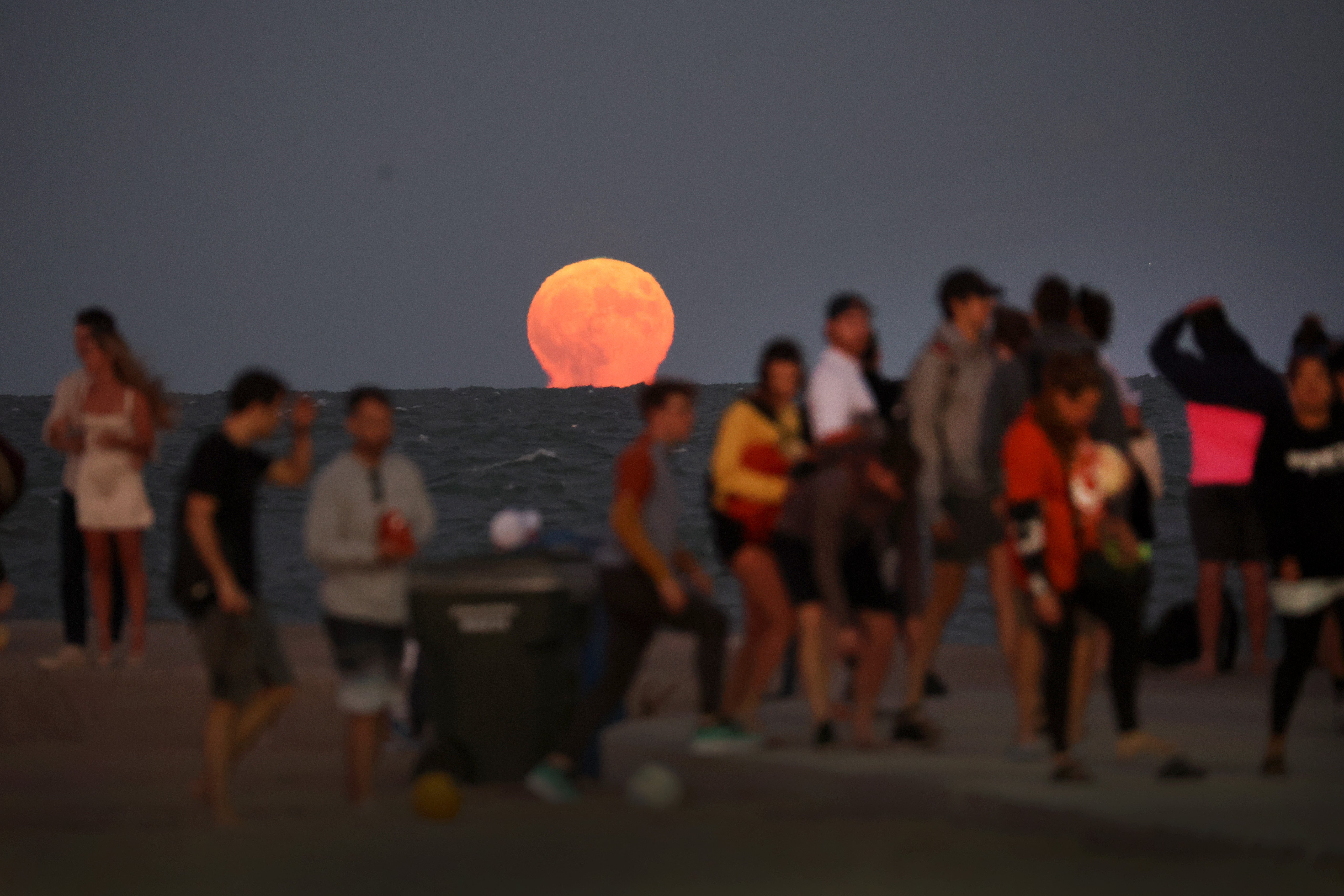 People stand at North Avenue Beach in Chicago, Illinois, as the the super blue moon rises in August 2023. A blue moon will overnight this weekend