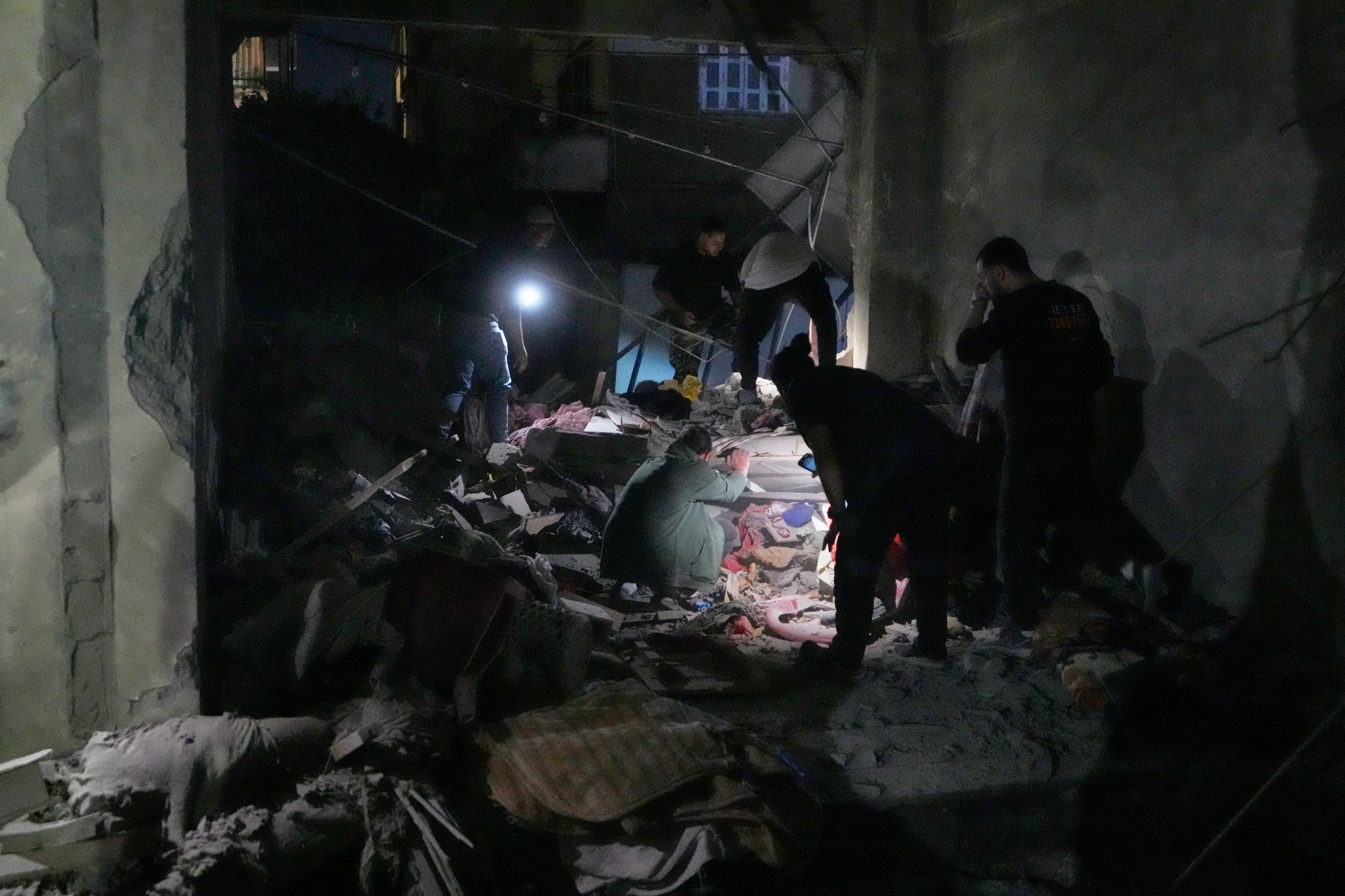 Rescue workers search for victims inside a destroyed apartment that was damaged by an Israeli airstrike in the southern port city of Sidon, Lebanon,