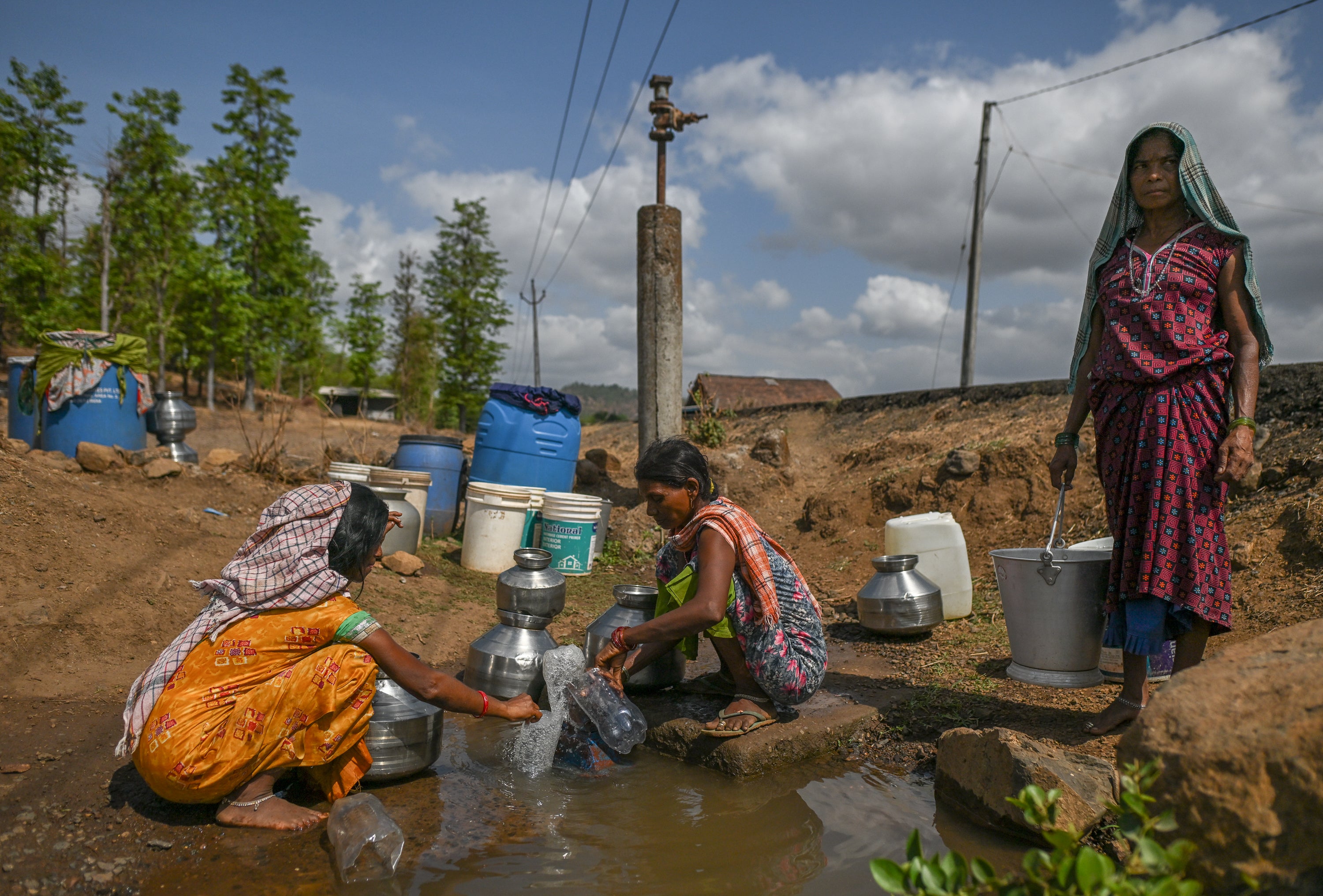 Women collect water from a stagnant and polluted source in a drought affected village in Kaprada, Gujarat, on 27 May 2026 (Getty)