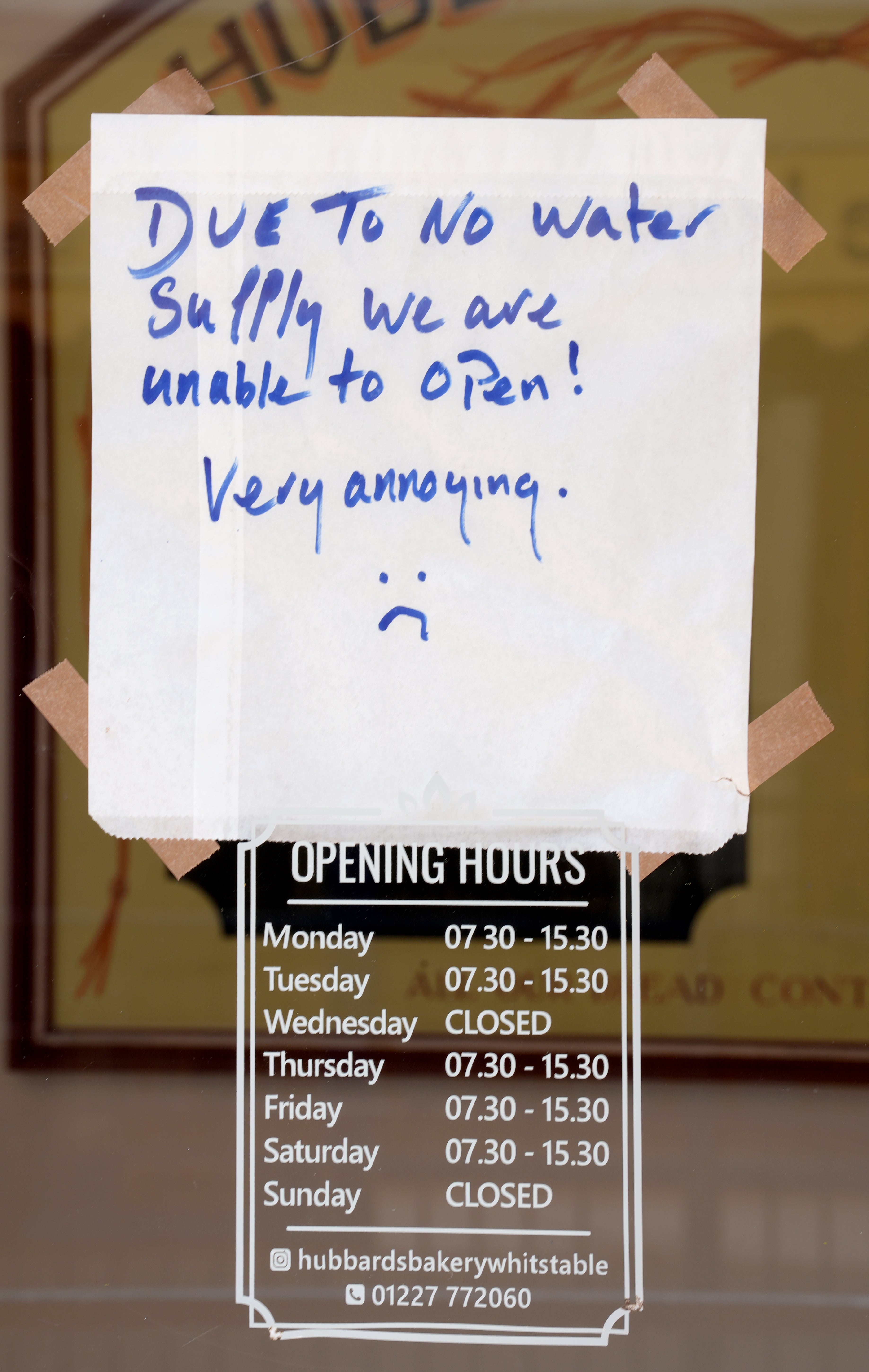 A sign announcing the temporary closure of a bakery in the shop window in Whitstable, Kent