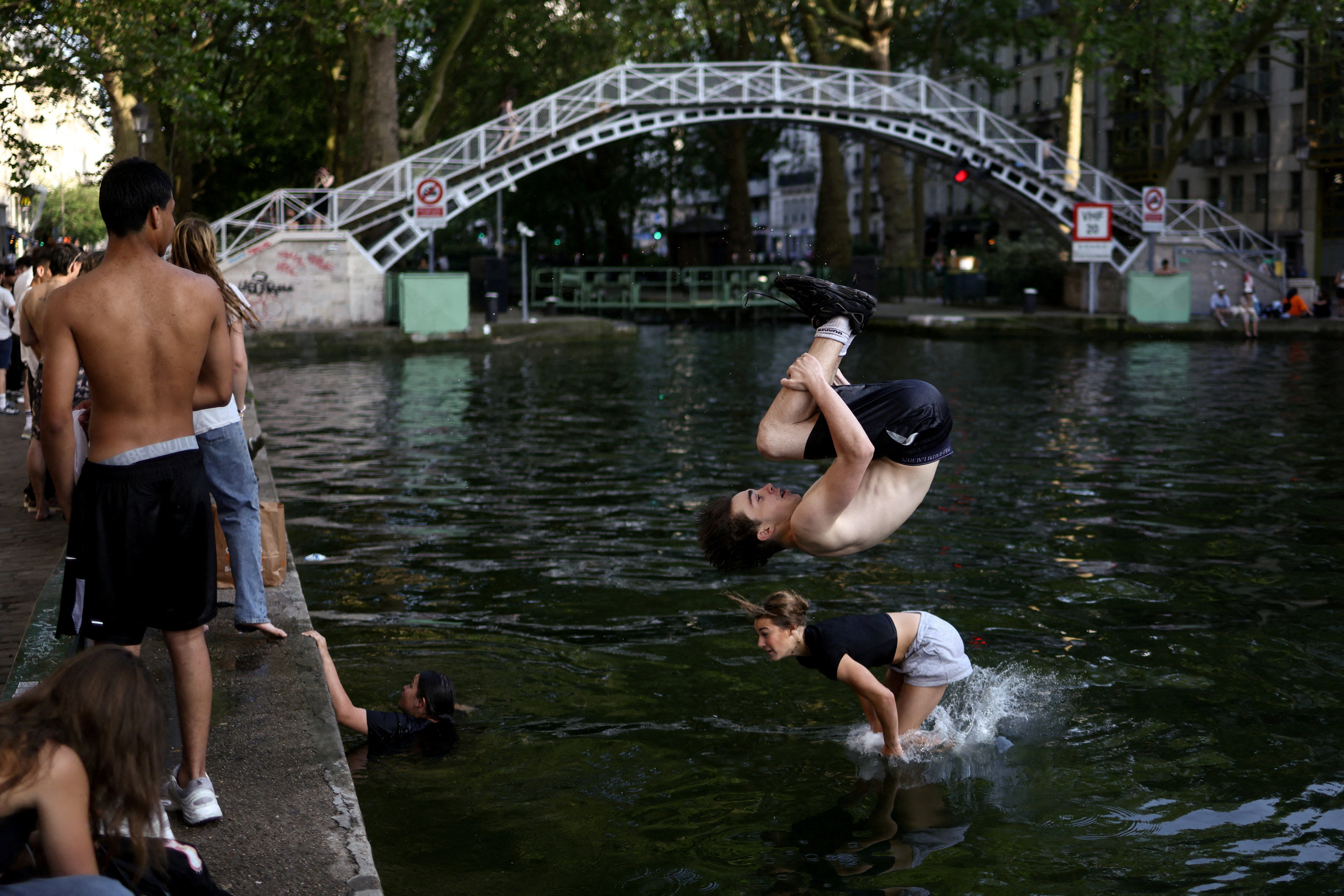 People jump into the Canal Saint-Martin amid a heatwave in Paris on Thursday