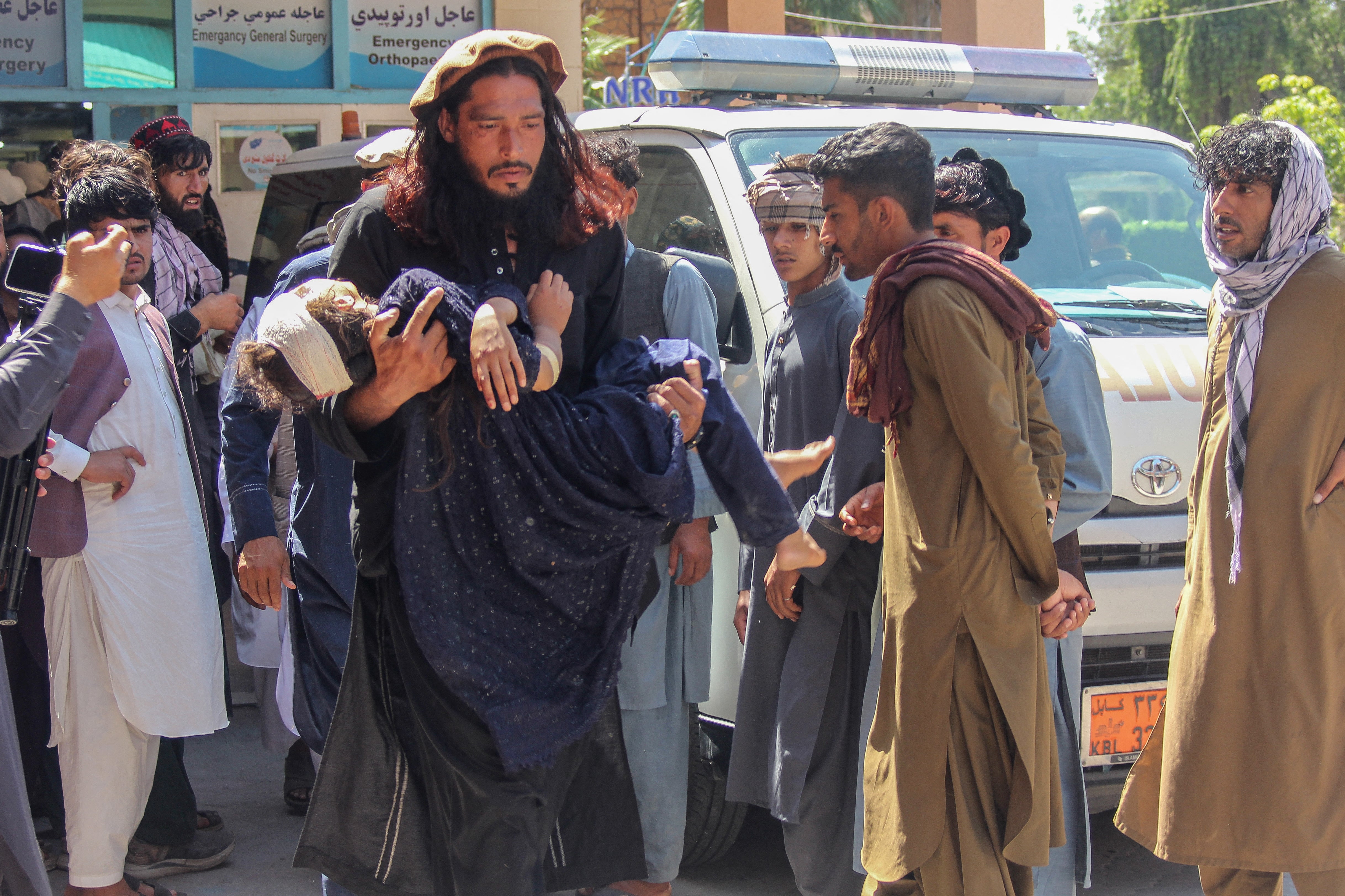 A man carries an injured girl to a local hospital after a truck carrying refugees crashes in Laghman, Afghanistan