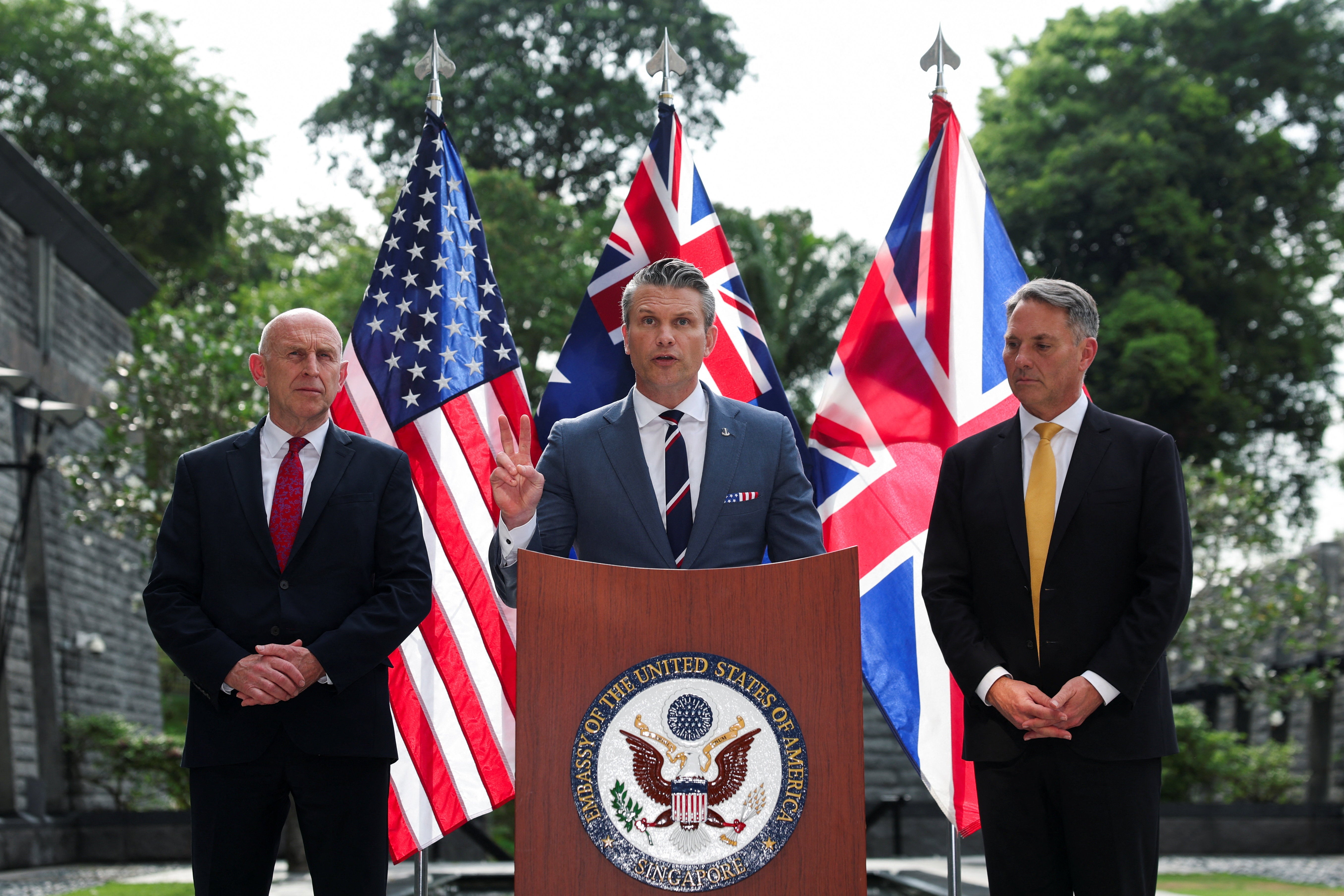 Australian Defence Minister Richard Marles and British Defence Secretary John Healey look on as U.S. Secretary of Defense Pete Hegseth speaks during an AUKUS Defence ministers' press huddle (Reuters)