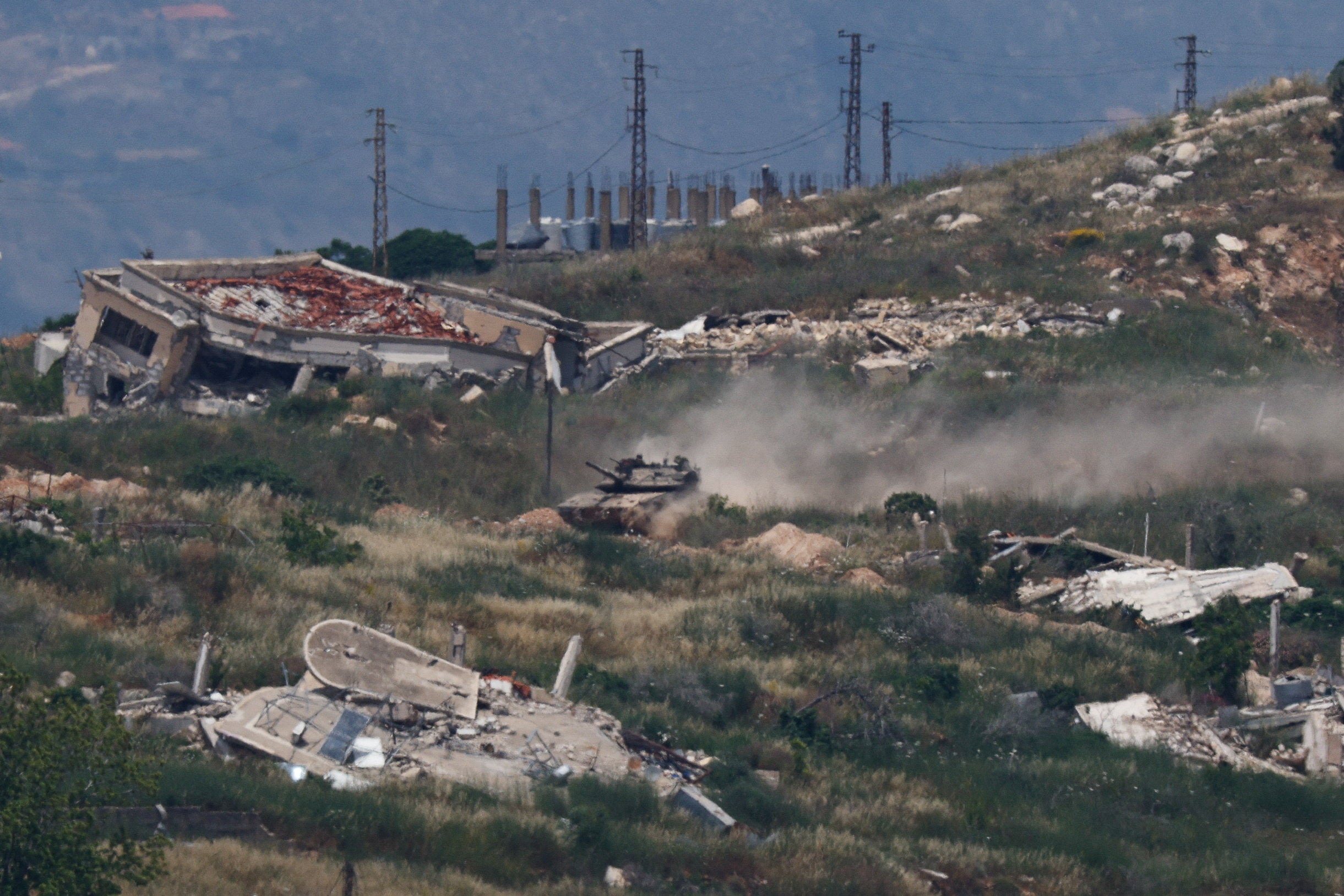 An Israeli tank maneuvers by destroyed buildings in southern Lebanon, as seen from Metula (Reuters)