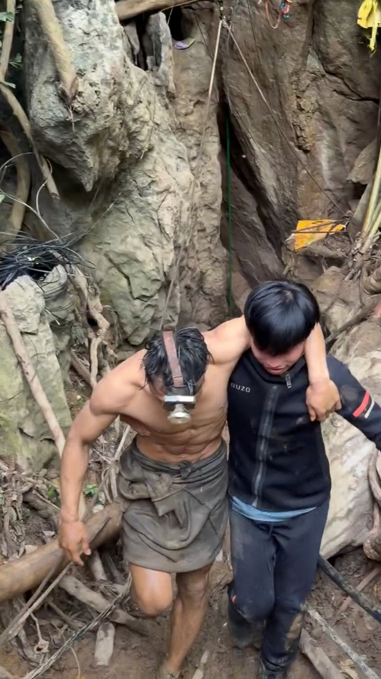 A rescued man is supported by a volunteer, after seven Lao nationals who had entered a cave to prospect for gold were trapped for more than a week when rising water blocked their exit, in Xaisomboun province, Laos, 30 May 2026, in this screen grab taken from social media video